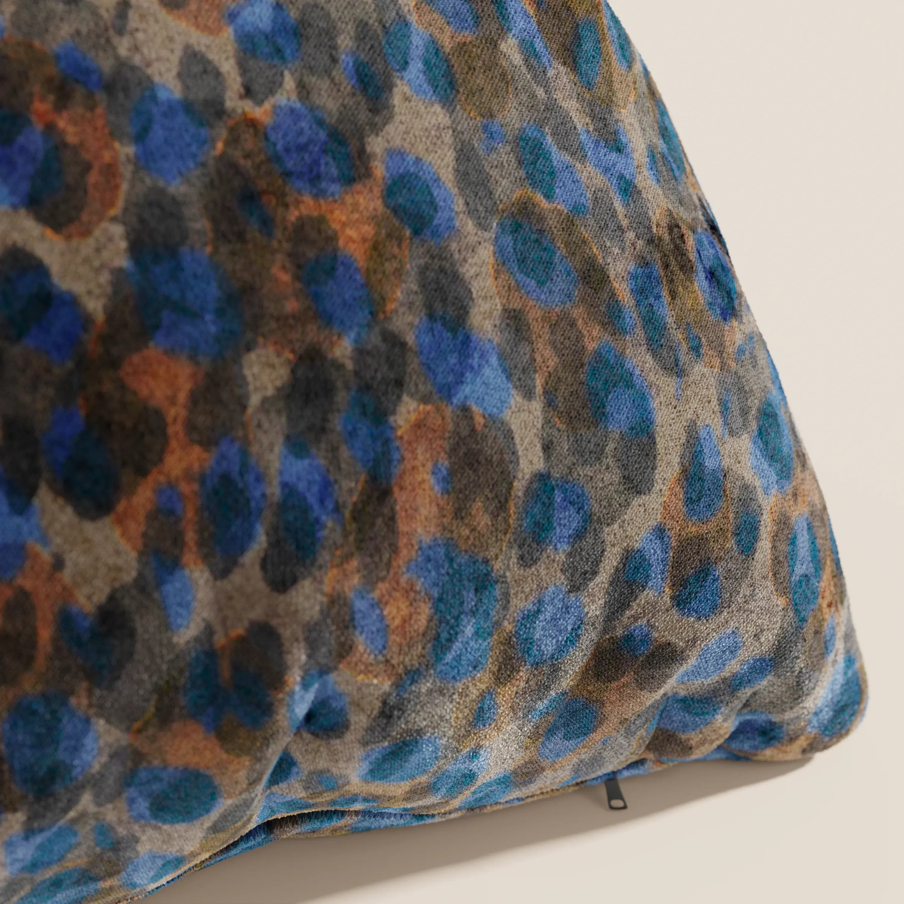 Primo piano del cuscino Brush di Divani.Store, realizzato in velluto blu impermeabile. Il cuscino moderno, disponibile in vari colori e dalla consistenza morbida, è appoggiato su una superficie chiara.