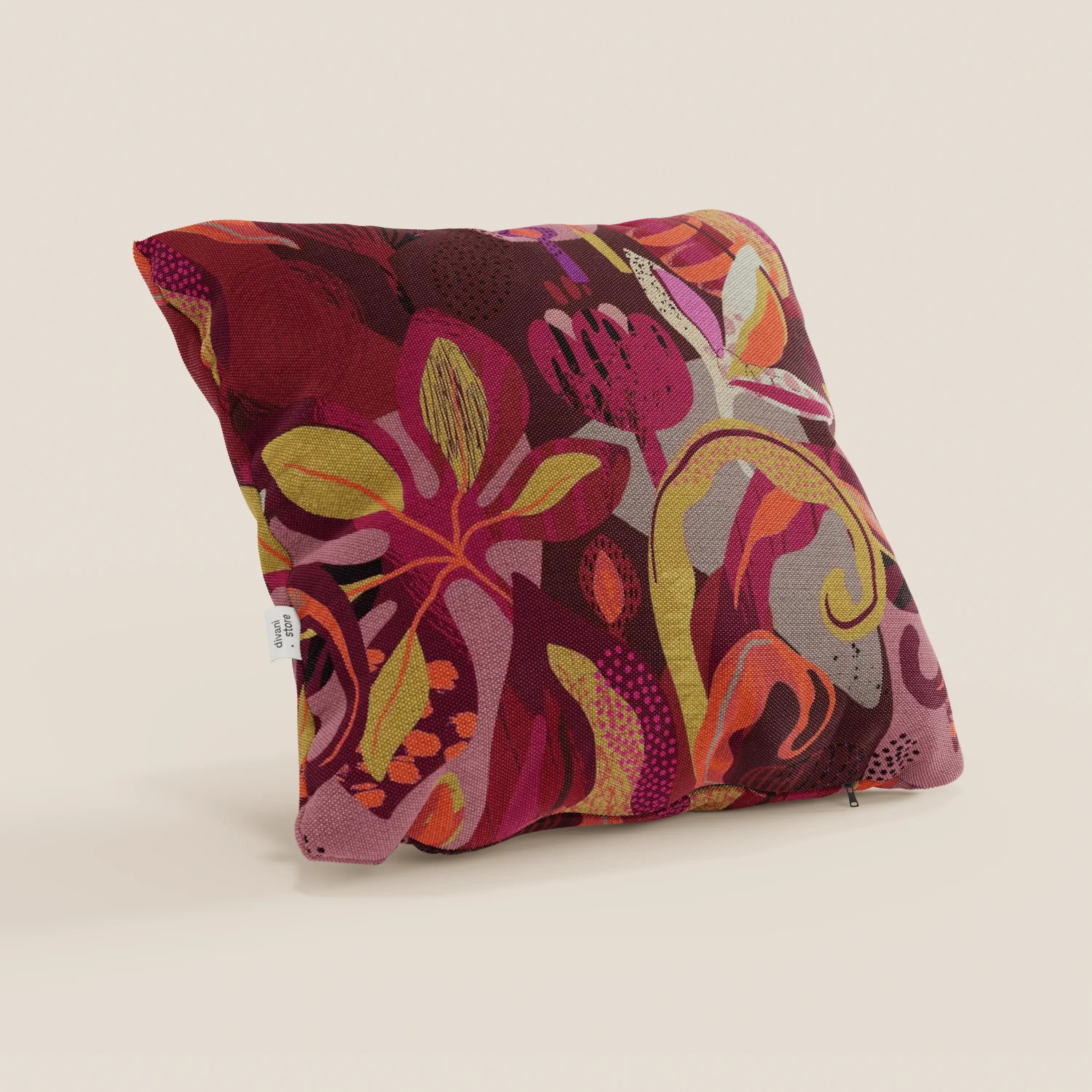 Il cuscino Joy di Divani.Store è un cuscino quadrato di 45x45 cm in fresco cotone rosso impermeabile con un vivace motivo floreale astratto multicolore e una piccola etichetta laterale bianca, su sfondo beige chiaro.