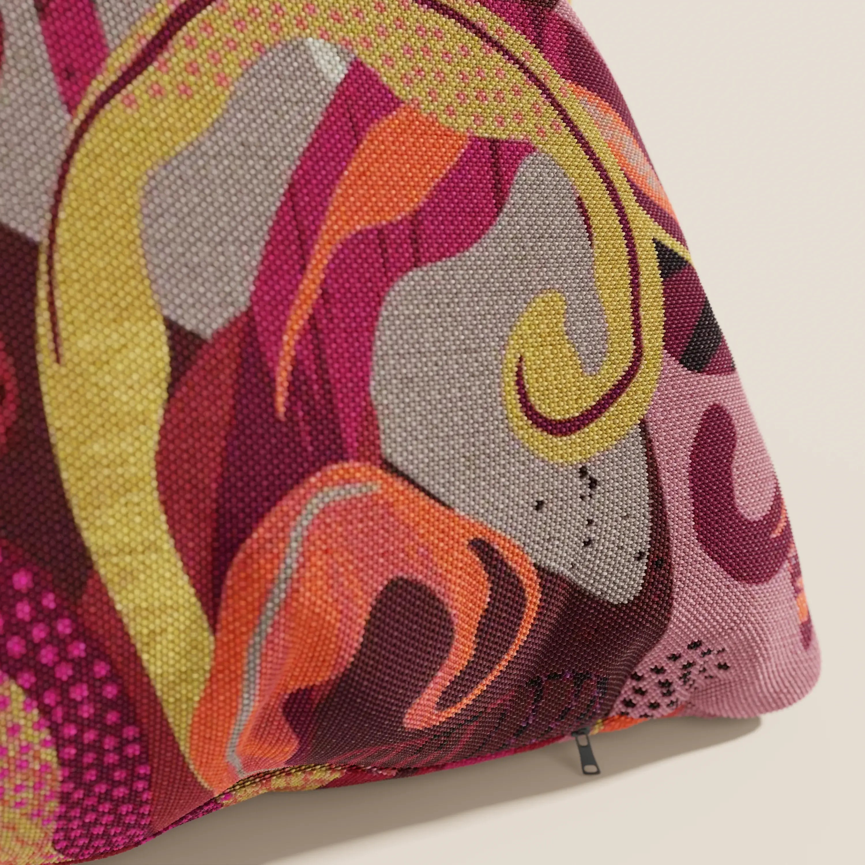 Un primo piano di Joy, un cuscino Divani.Store a fantasie multicolor rosse in fresco cotone impermeabile, perfetto per cuscini lavabili 45x45 cm. Elegante e pratico, con zip nera sul bordo.