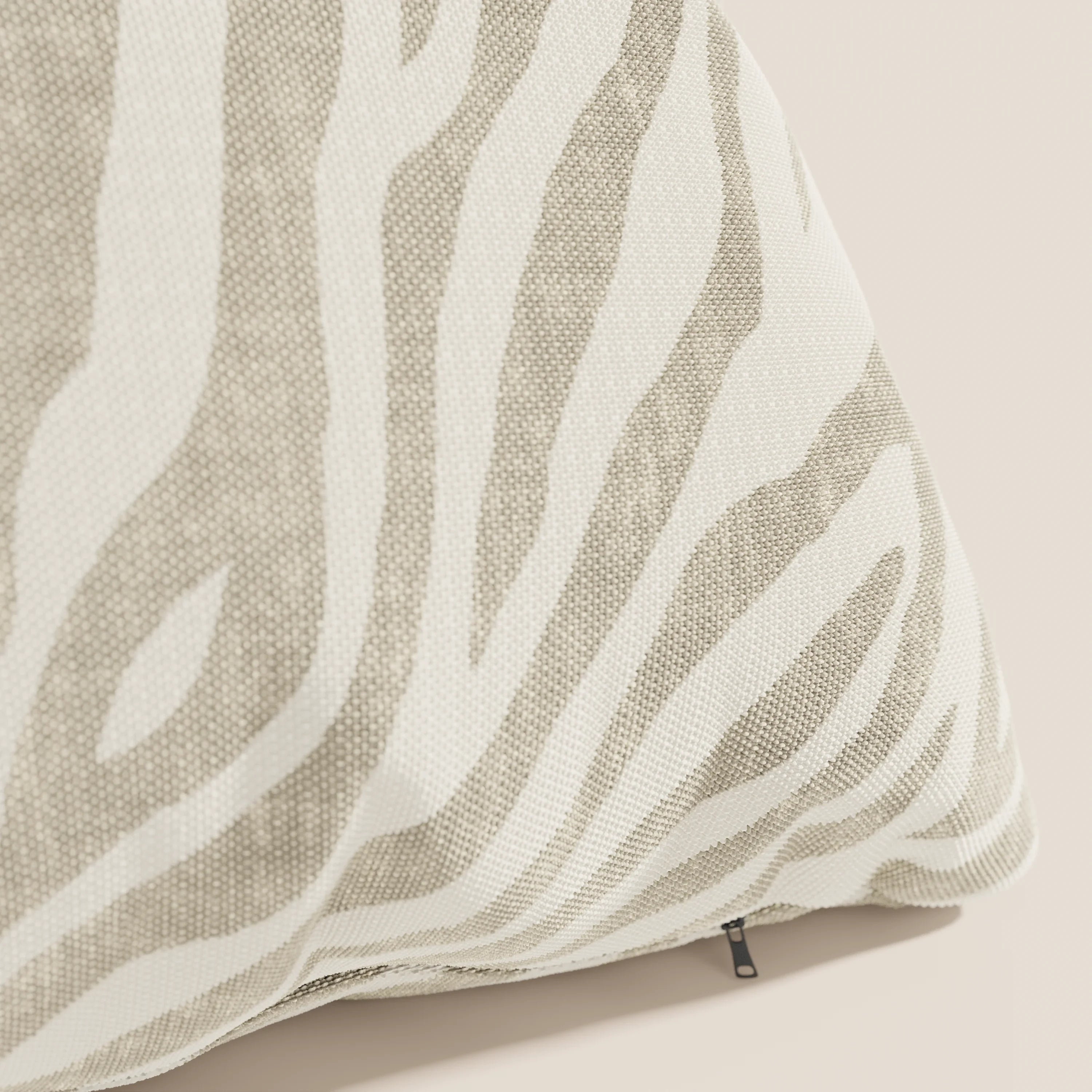 Un primo piano dello Stripe cuscini geometrici in tessuto Idrorepellente di Divani.Store, che mostra il motivo zebrato beige e la trama intrecciata, con un tiretto nero sul bordo inferiore.