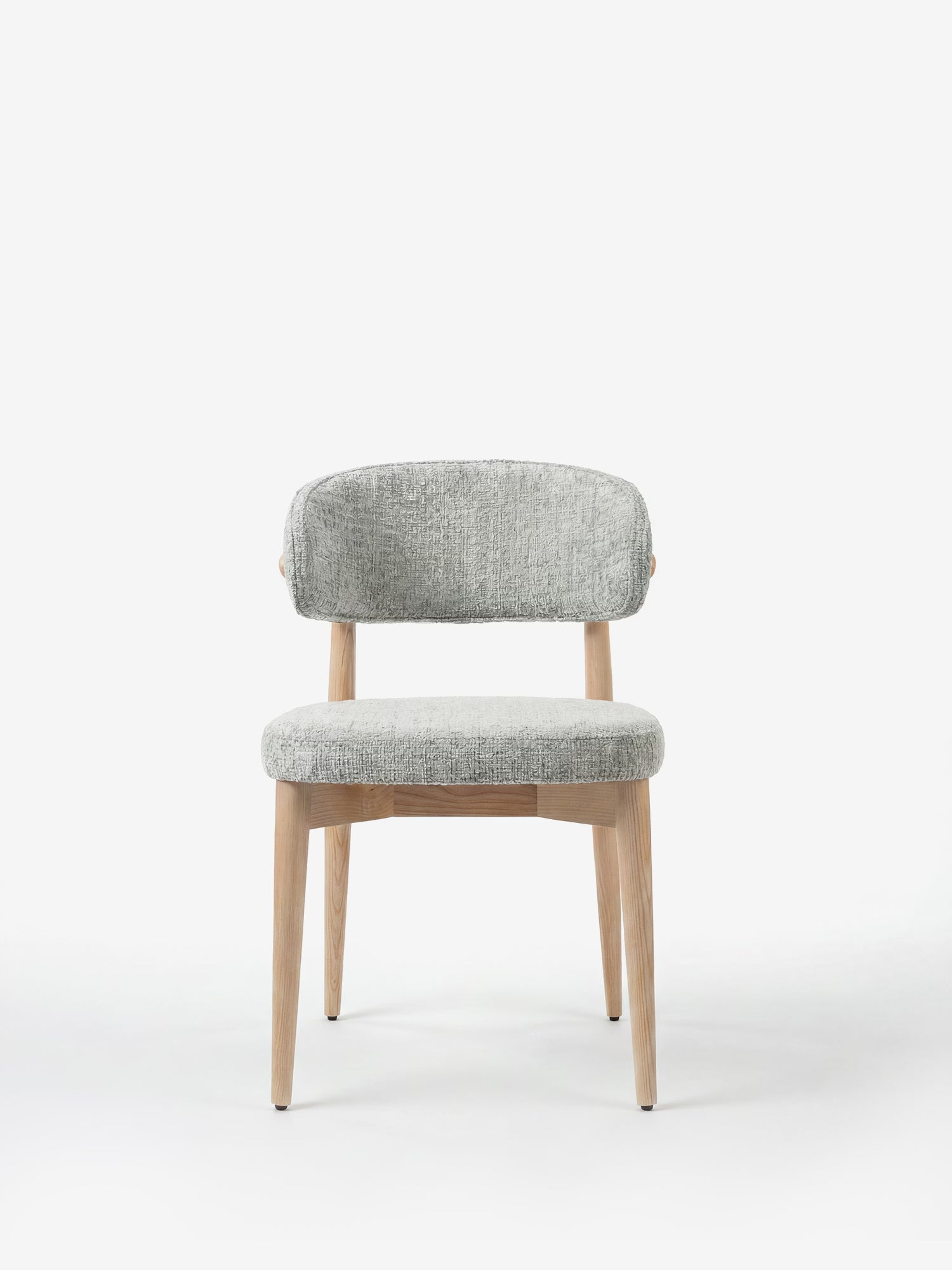 La sedia imbottita Dafne di Divani.Store presenta gambe e struttura in rovere massello naturale, uno schienale curvo ed è rivestita in tessuto ciniglia certificato OEKO-TEX®. Presentata su uno sfondo bianco per un look pulito e minimalista.