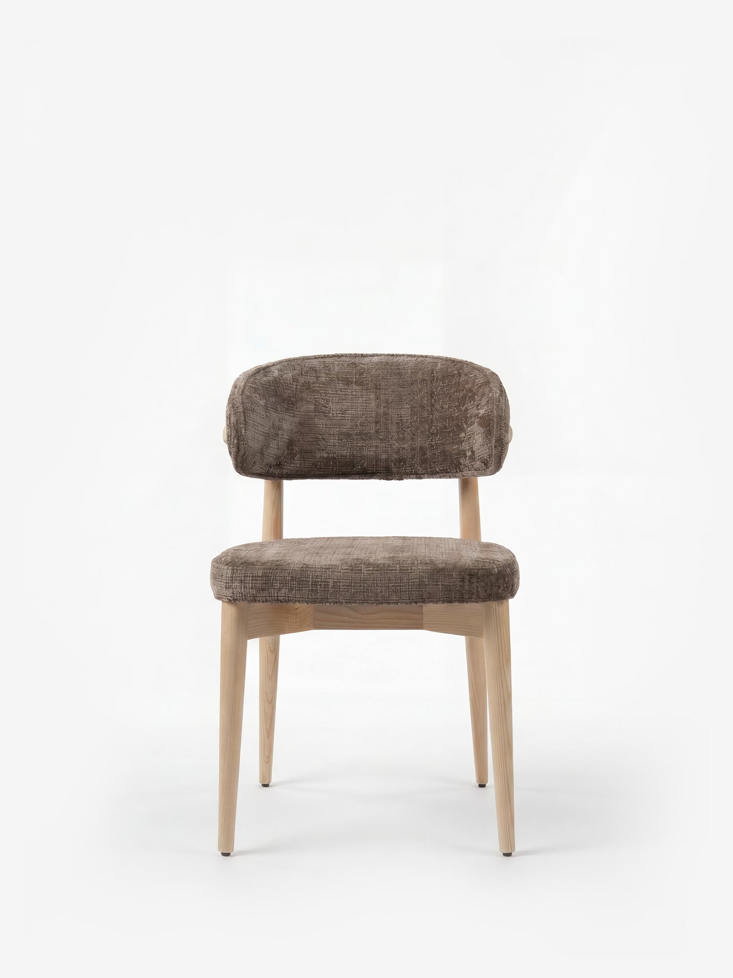 La sedia imbottita Dafne di Divani.Store presenta una struttura in rovere massello naturale e gambe in legno chiaro, con schienale basso e curvo e seduta in tessuto chenille certificato OEKO-TEX® color marrone vellutato, qui raffigurata su uno sfondo bianco a tinta unita.