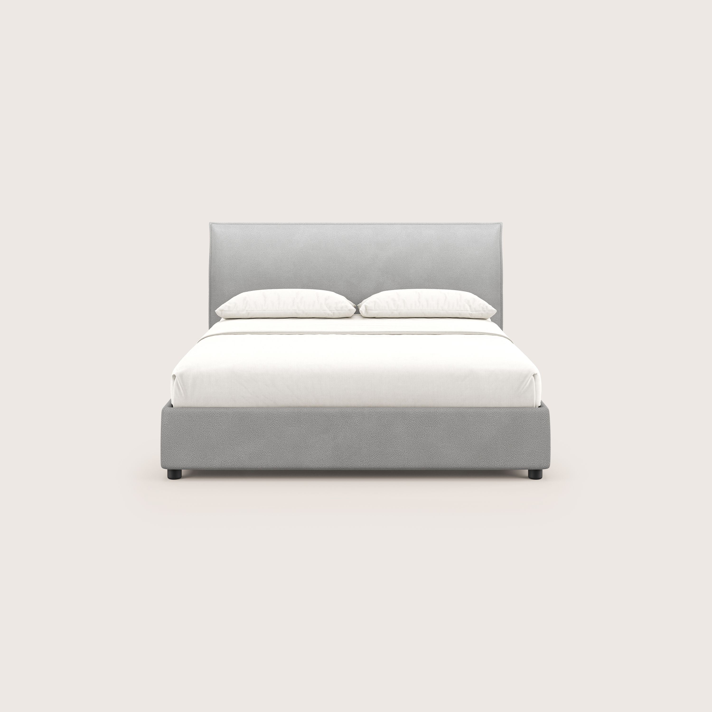 Il letto contenitore Nina di Letti.store è caratterizzato da un design italiano minimale in microfibra grigia antimacchia con struttura e testata imbottite, ordinate con lenzuola e cuscini bianchi su uno sfondo beige chiaro.