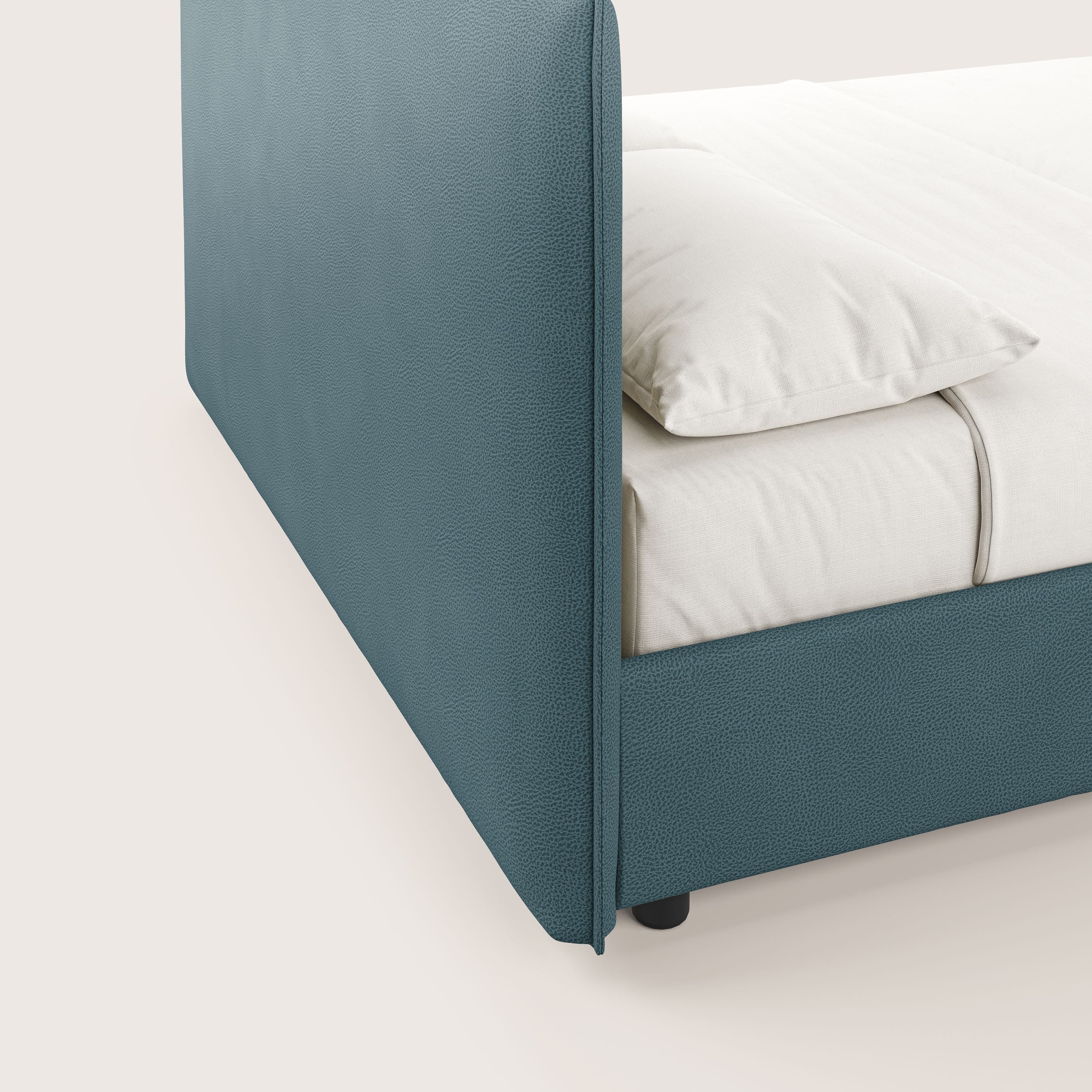 Primo piano del letto contenitore Nina di Letti.store: un letto minimal in microfibra antimacchia color petrolio con struttura e testata imbottite e strutturate, ordinatamente realizzato con lenzuola bianco sporco, che rispecchia il design di ispirazione italiana.