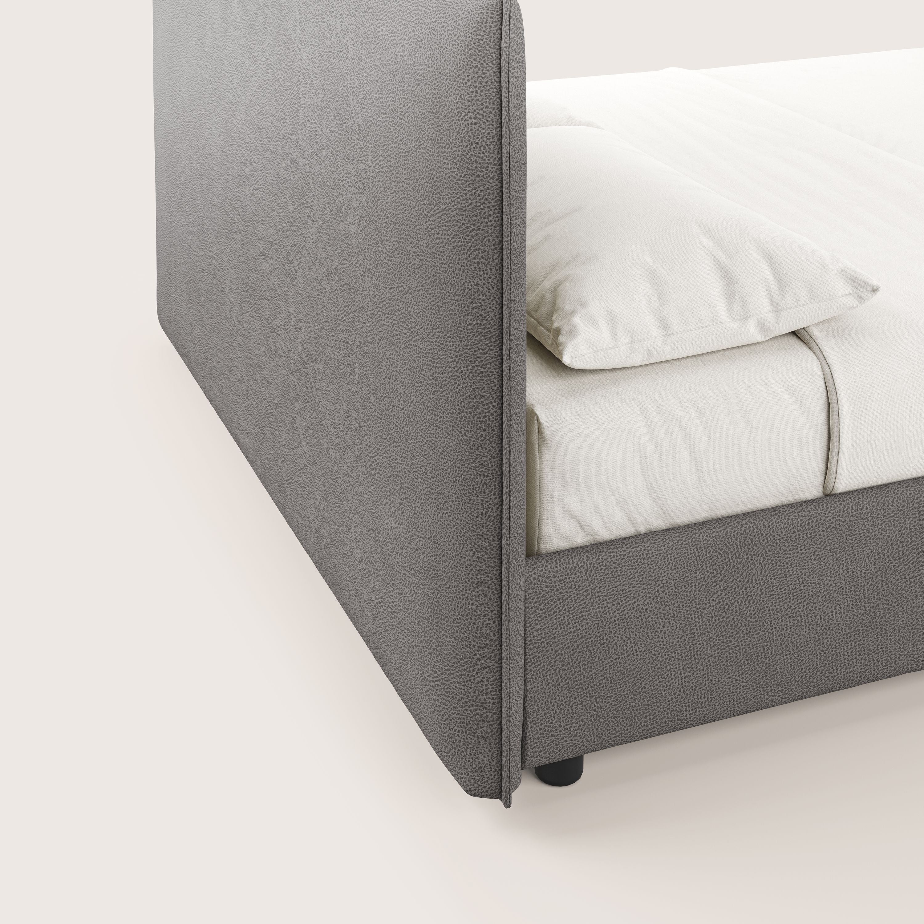 Primo piano del letto contenitore Nina di Letti.store, dal design minimalista italiano con struttura in microfibra antracite antimacchia e biancheria da letto ordinata in bianco sporco per un look pulito e moderno.