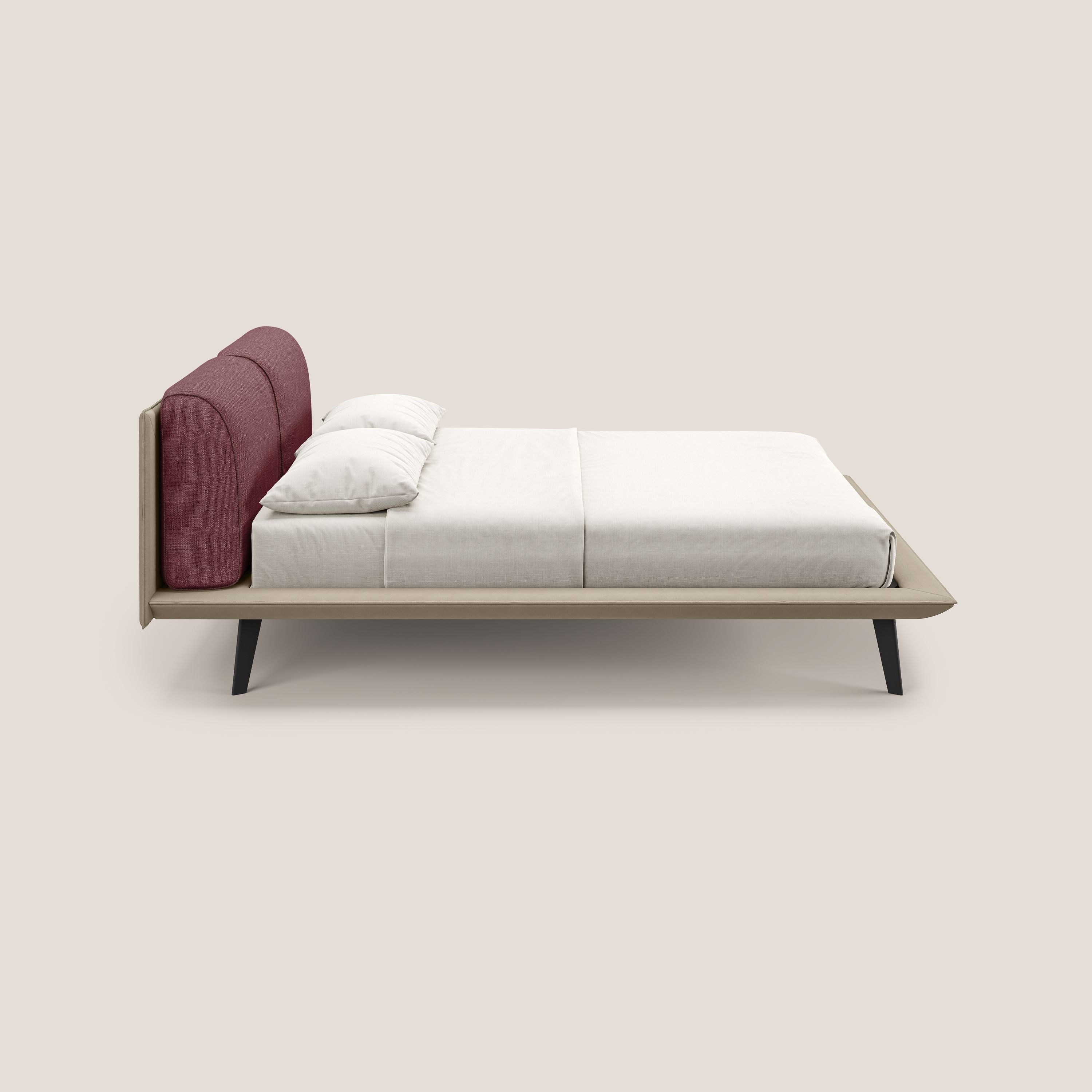 Vista laterale di Petra letto di design di Letti.store, con tessuto impermeabile bicolore T11/T06 tortora-rosso, cuscini in piuma, testata imbottita rosso intenso, gambe in mogano, biancheria da letto bianca e due cuscini su sfondo beige chiaro.
