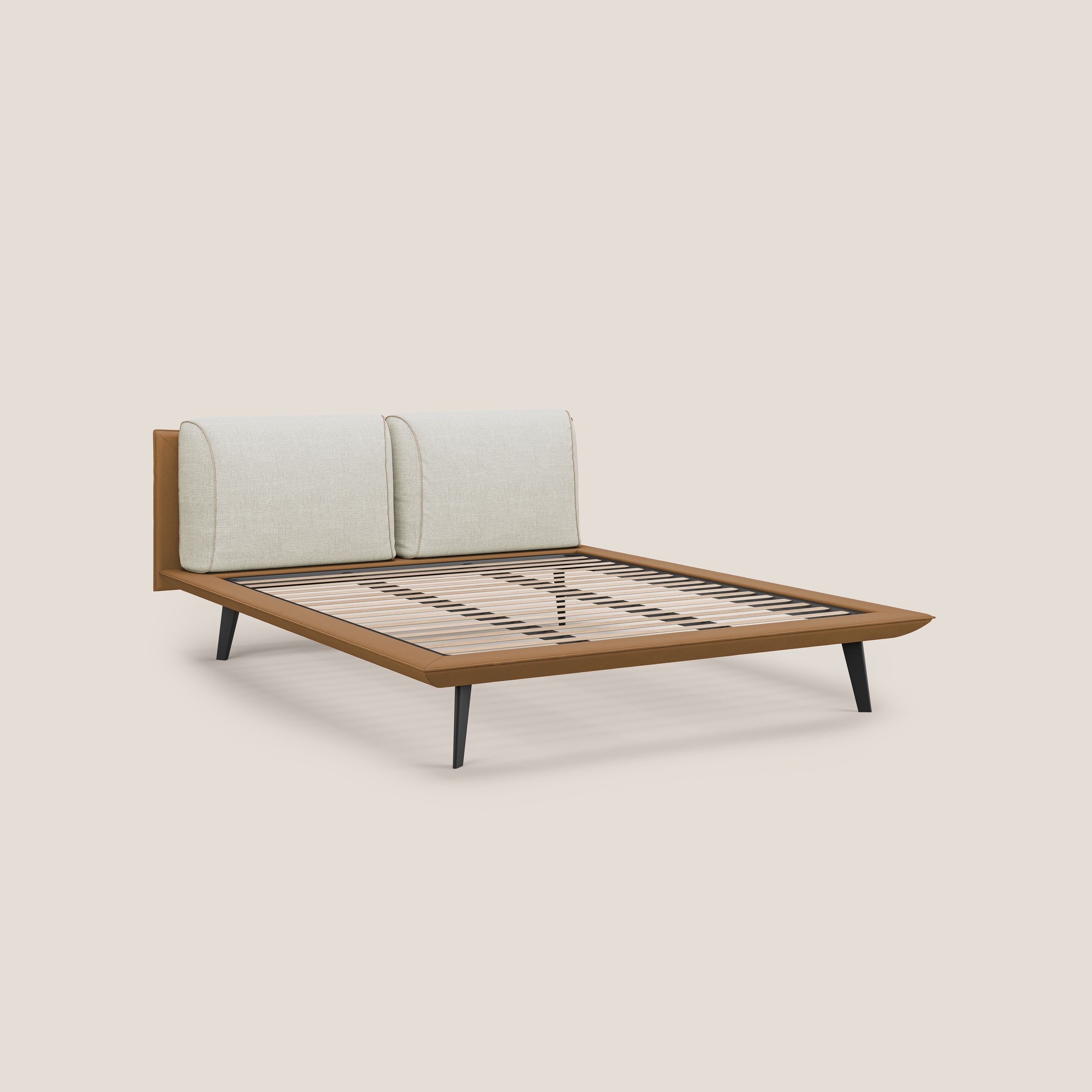 Il letto di design Petra di Letti.store è caratterizzato da un tessuto impermeabile bicolore (T11 cuoio e T06 panna), da una struttura minimalista con piedi in mogano massiccio e da due grandi cuscini in piuma sulla testata. Rete ortopedica doghe a vista per il sostegno.