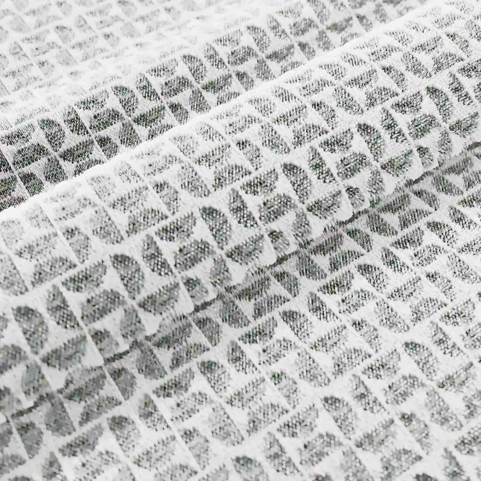 Primo piano del cuscino Naxos Decoro 45x45 in lino di Divani.Store, che mette in risalto il tessuto in lino bianco con motivo a rombi in rilievo e morbide pieghe che esaltano l'elegante disegno geometrico tridimensionale.