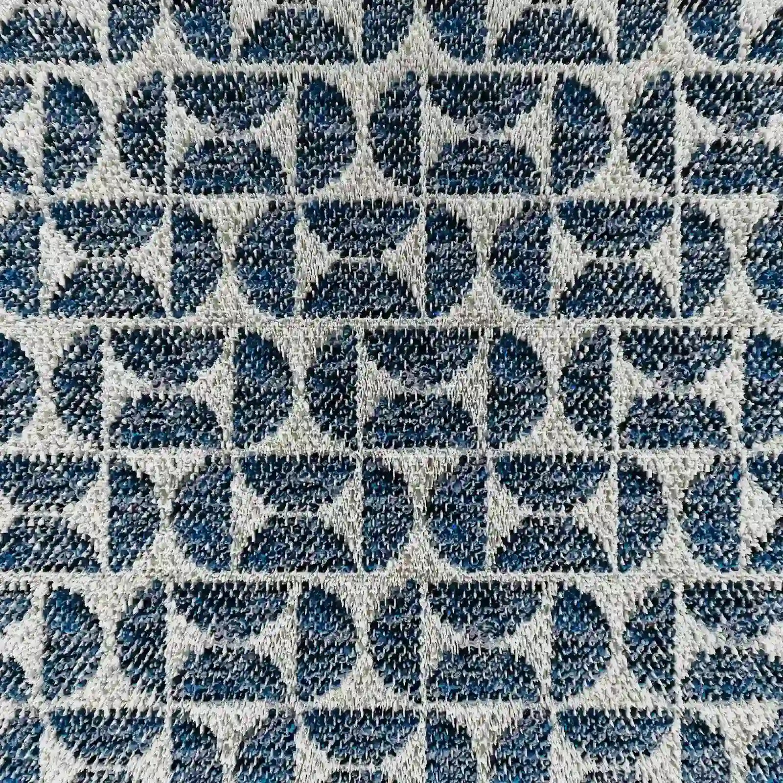 Primo piano del modello Naxos Cuscino Decoro 45x45 in lino di Divani.Store, che mette in risalto l'elegante tessuto in lino e il motivo geometrico a rilievo con semicerchi e rettangoli blu scuro su sfondo grigio chiaro, per un look raffinato e moderno.