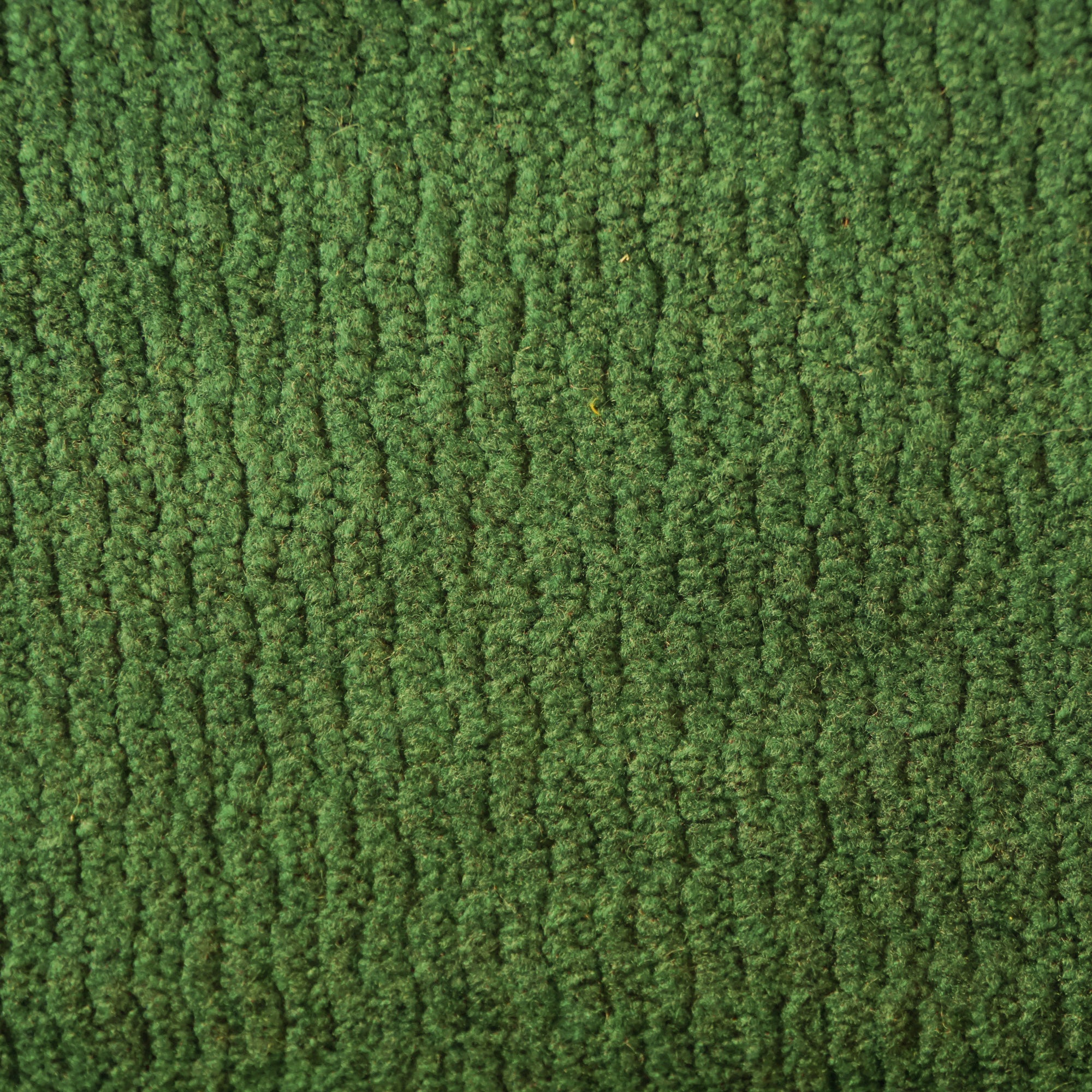 Primo piano di T32 Kendal di Divani.Store: un tappeto verde a coste con una sensazione di microfibra morbida e soffice. La sua superficie presenta una leggera variazione di colore rispetto alla texture e presenta un trattamento impermeabile e antimacchia.