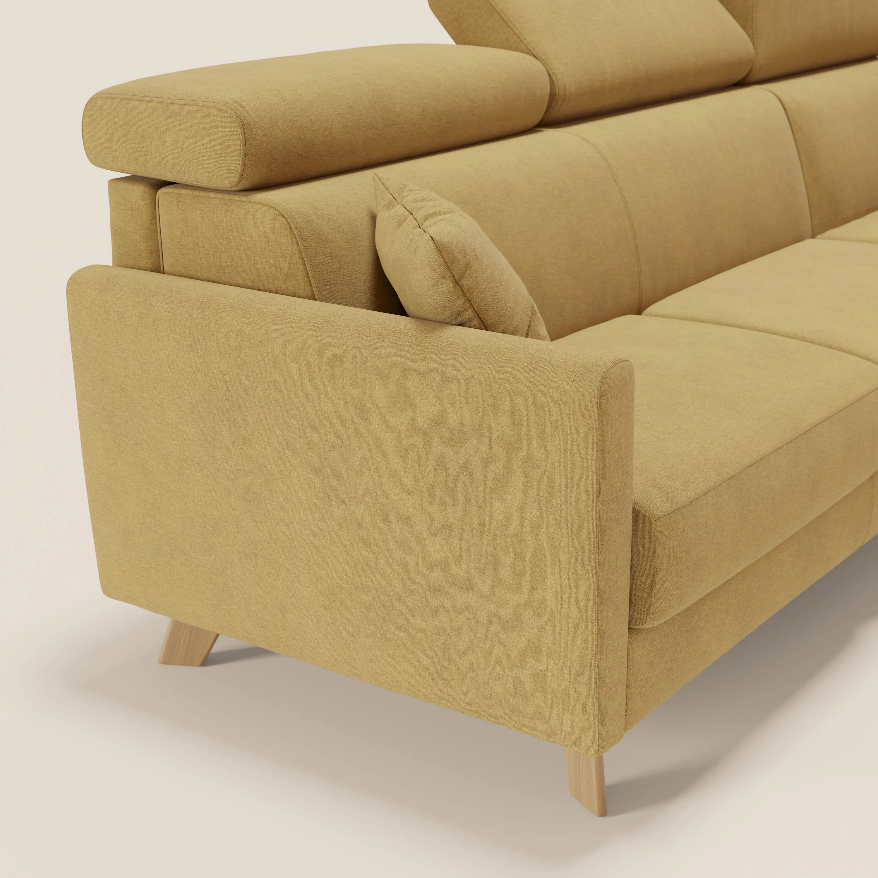 Primo piano del lato sinistro di Francy divano letto angolare sfoderabile in tessuto giallo T17 di Divani.Store, caratterizzato da poggiatesta reclinabile, bracciolo angolare, cuscino laterale coordinato, gambe in legno e chaise longue contenitore su sfondo beige chiaro.