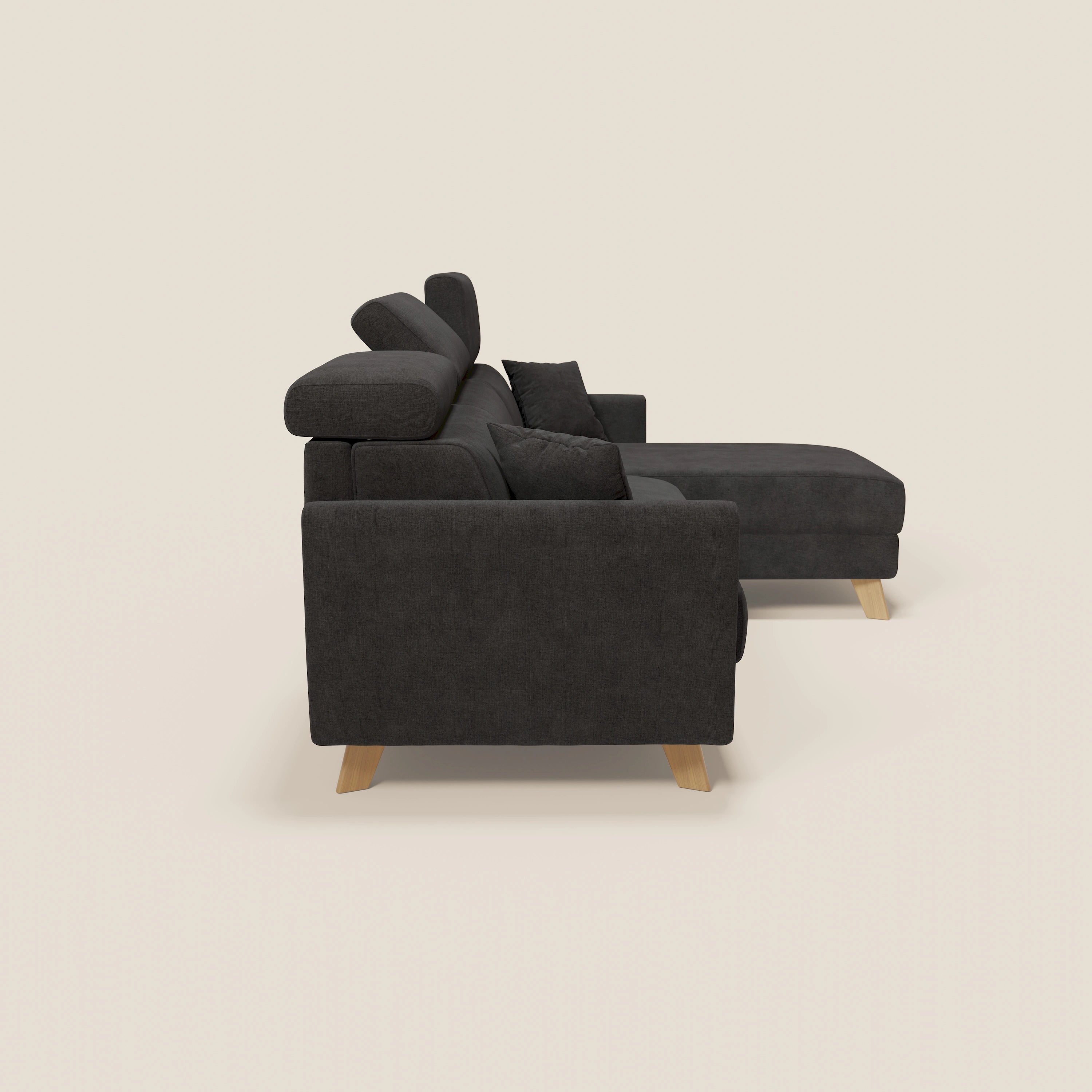 Vista laterale del divano letto angolare sfoderabile Francy di Divani.Store in smacchiabile T17 nero, con chaise longue destra, poggiatesta reclinabili, gambe in legno chiaro, cuscini spessi e due cuscini. Design moderno Stile Nordico su sfondo beige.