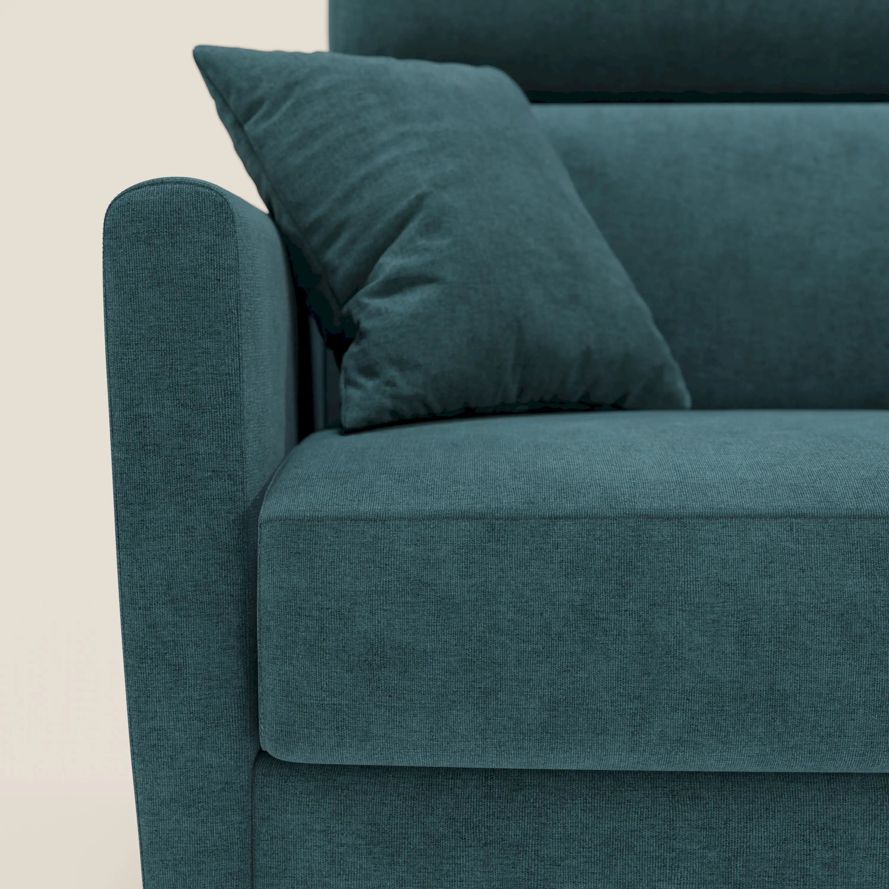 Primo piano del divano letto angolare sfoderabile Francy di Divani.Store in tessuto T17 petrolio, con cuscino coordinato, penisola contenitore, poggiatesta reclinabili e stile nordico su sfondo beige.