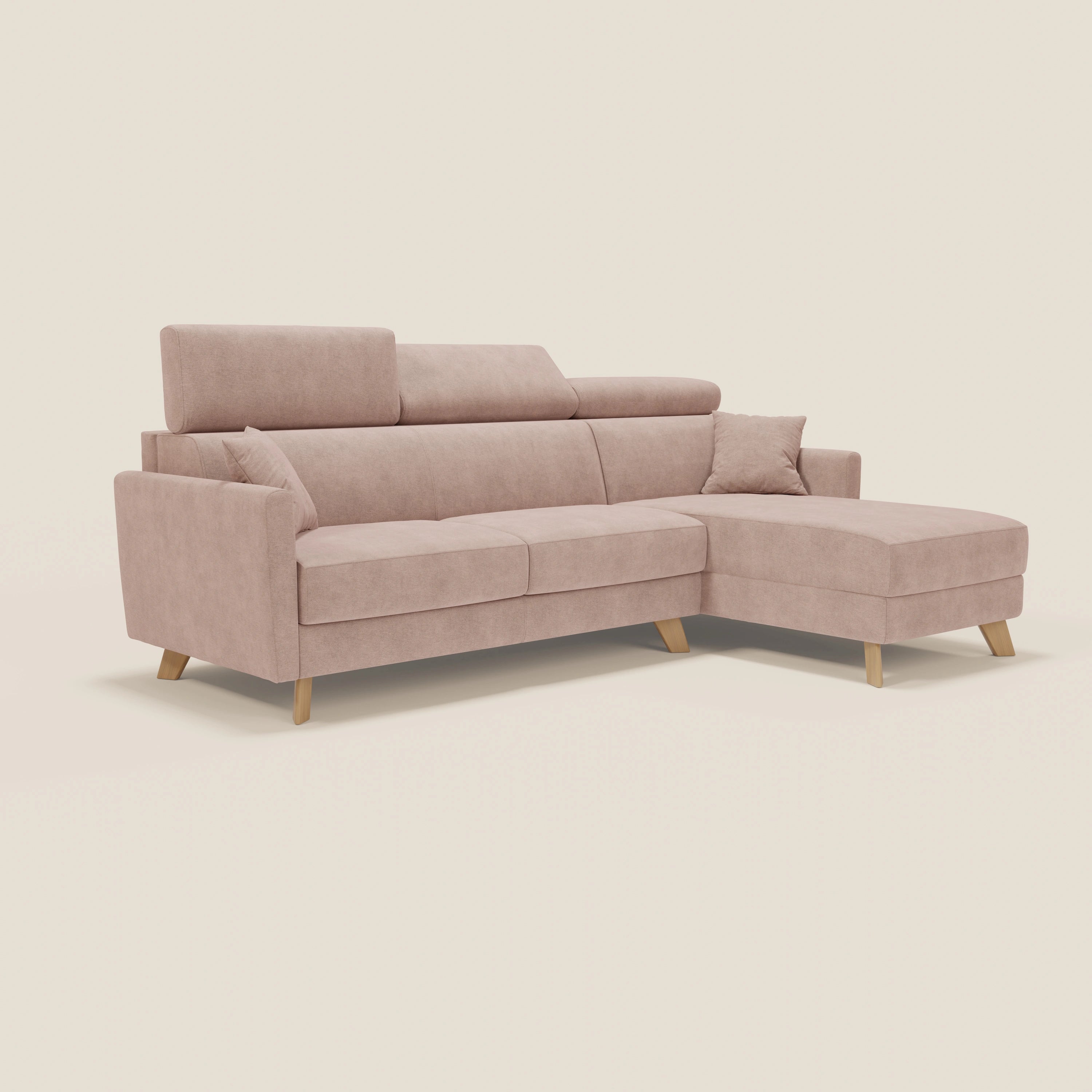 Il divano letto a L Francy di Divani.Store è caratterizzato da un tessuto lavabile rosa T17, da una chaise longue, da poggiatesta reclinabili e da un cuscino coordinato, con gambe in legno e braccioli angolati, su uno sfondo beige semplice.