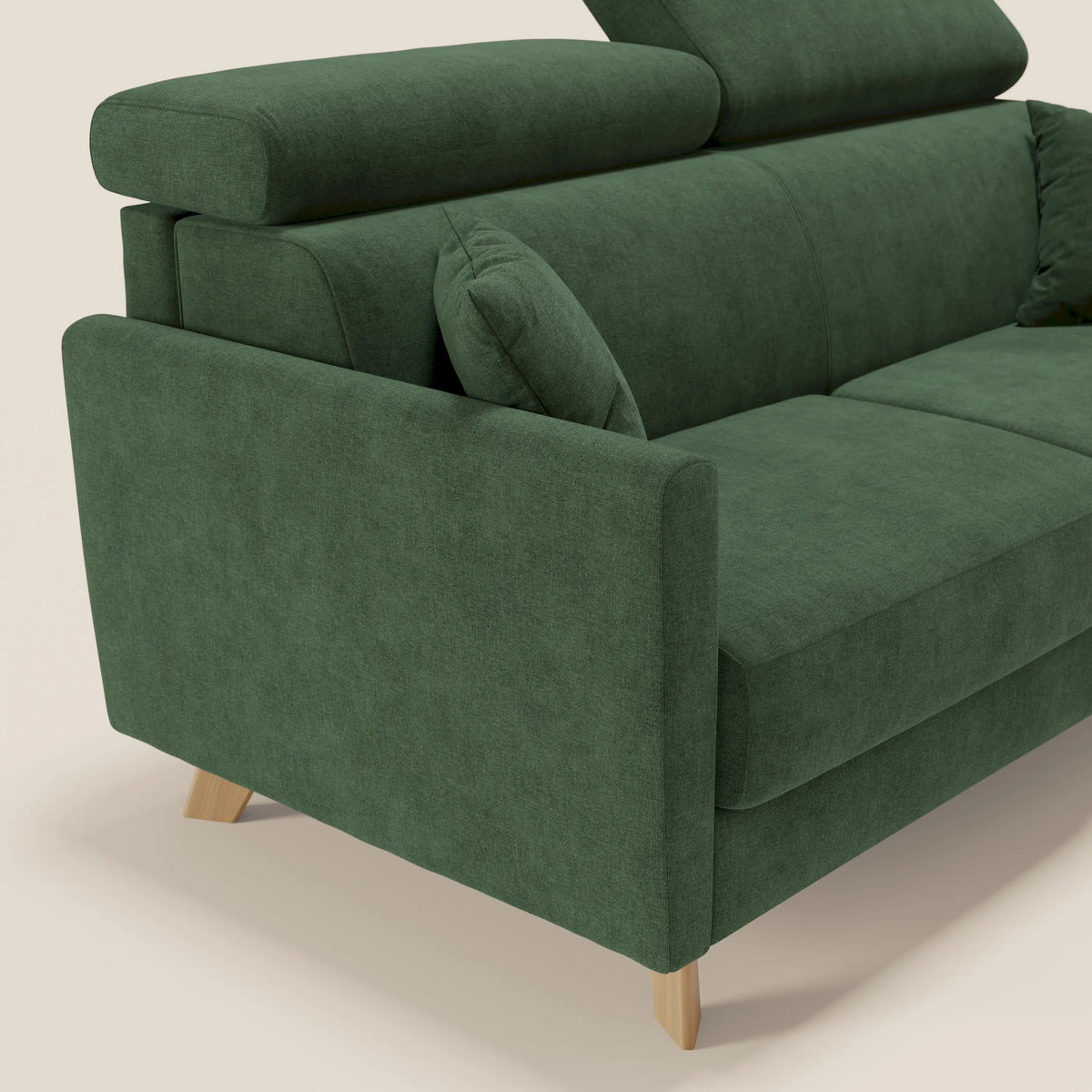 Primo piano del divano letto matrimoniale Francy di Divani.Store, qui presentato nella versione in tessuto verde T17, impermeabile e antimacchia. Il divano misura 180 cm ed è dotato di poggiatesta regolabili, cuscini coordinati, braccioli dritti e gambe in legno chiaro. È presentato su uno sfondo neutro a tinta unita che ne esalta le linee pulite e il design contemporaneo.