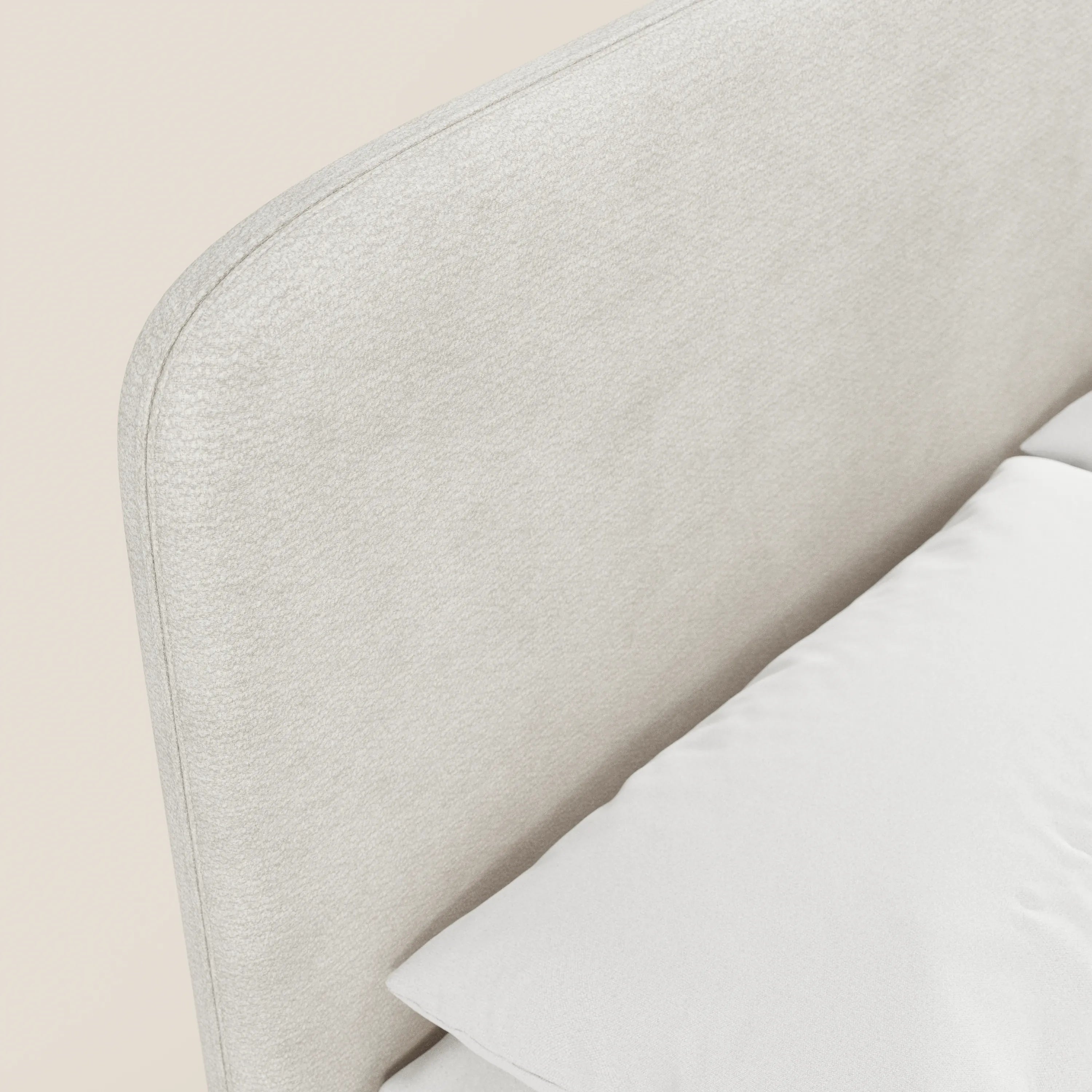 Primo piano del letto imbottito KAELOS Letto Minimal di Letti.store, caratterizzato da una testiera in tessuto ciniglia grigio chiaro con bordi arrotondati, gambe alte e un vano contenitore. Un cuscino bianco contribuisce a creare un’atmosfera accogliente e neutra nella camera da letto.