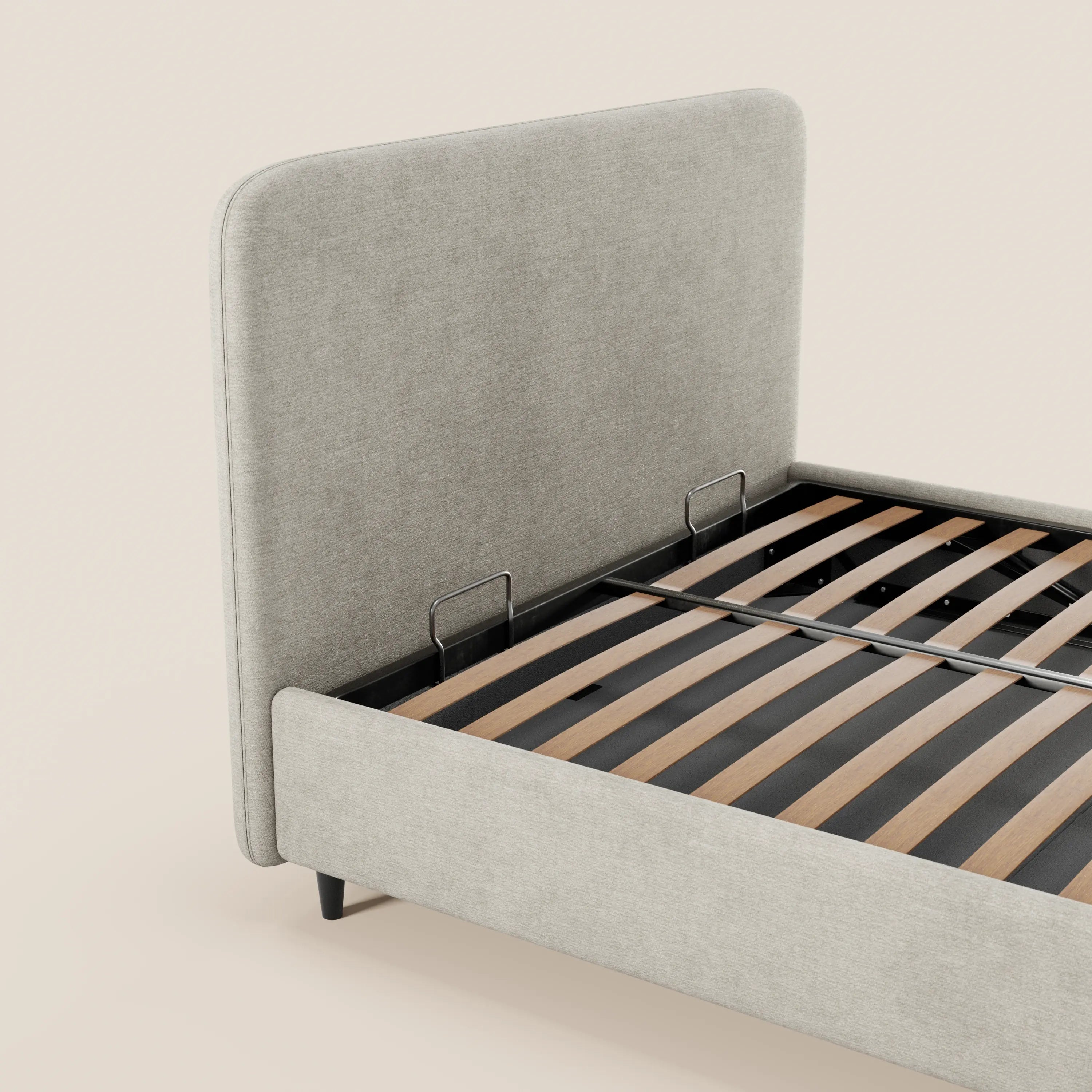 Il letto imbottito KAELOS minimal di Letti.store presenta una testiera arrotondata in ciniglia, gambe alte e un vano contenitore. Il rivestimento grigio chiaro e il design essenziale risaltano sullo sfondo beige, con doghe in legno scuro e due supporti in metallo.