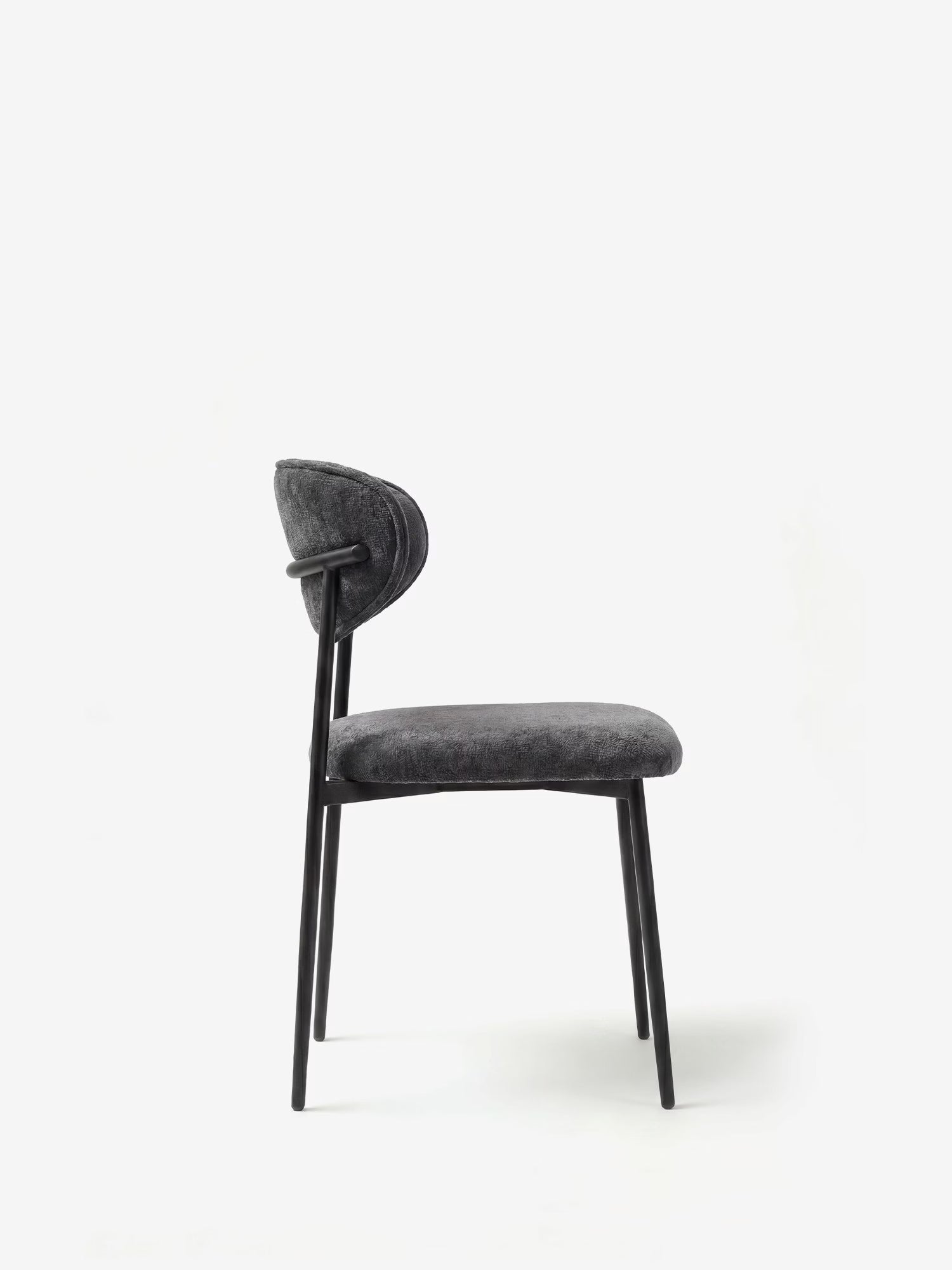 Una vista laterale della Luce Sedia, imbottita in morbido tessuto ciniglia di Divani.Store, caratterizzata da seduta e schienale scuri, sottili gambe in metallo nero, design senza braccioli e uno schienale leggermente ricurvo, il tutto su uno sfondo bianco a tinta unita.