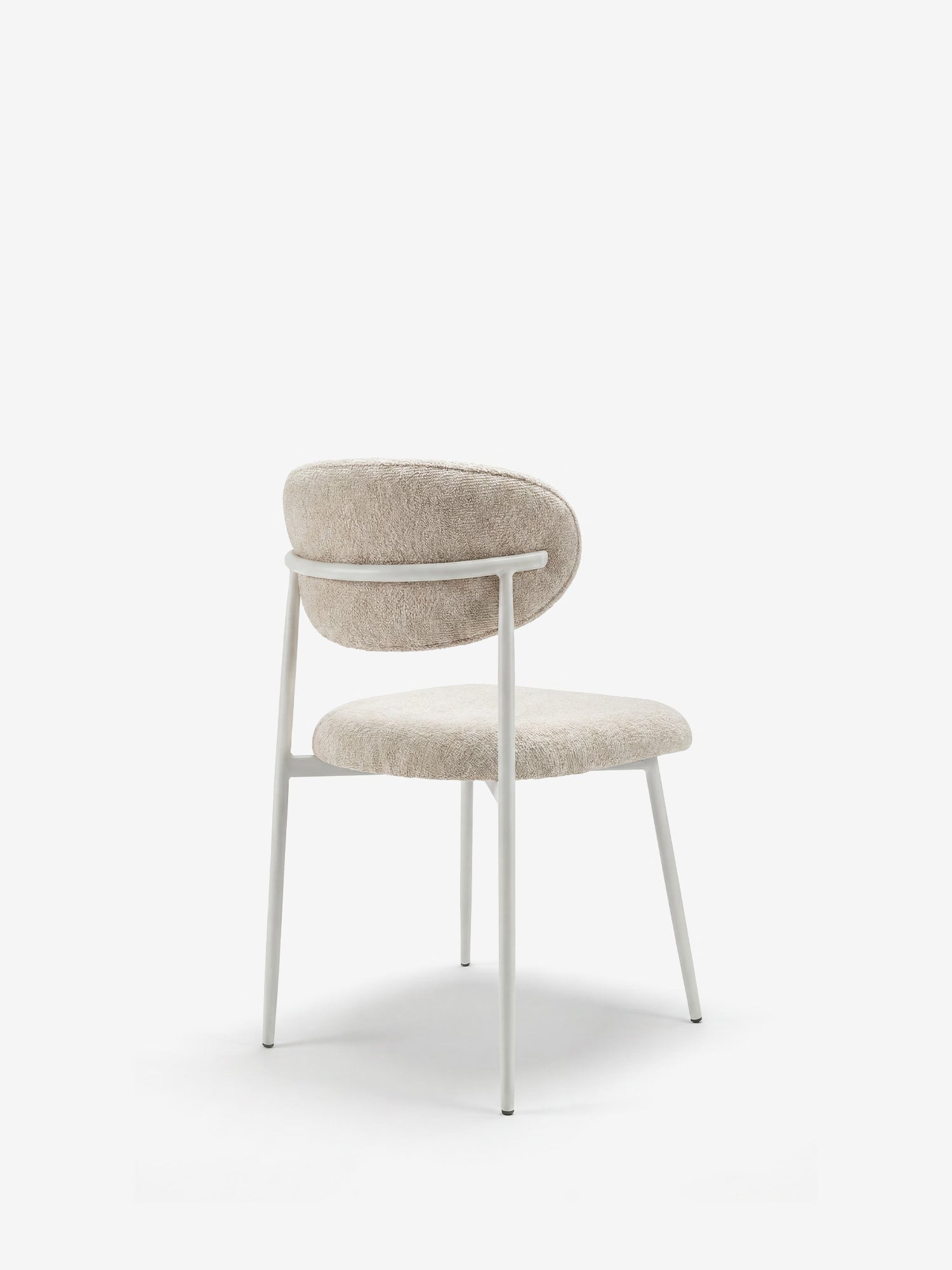 La poltrona Luce Sedia imbottita di Divani.Store presenta uno schienale ricurvo e un tessuto testurizzato color bianco sporco, con un design minimalista e gambe angolate in metallo bianco dalle linee slanciate, perfette per gli spazi contemporanei.