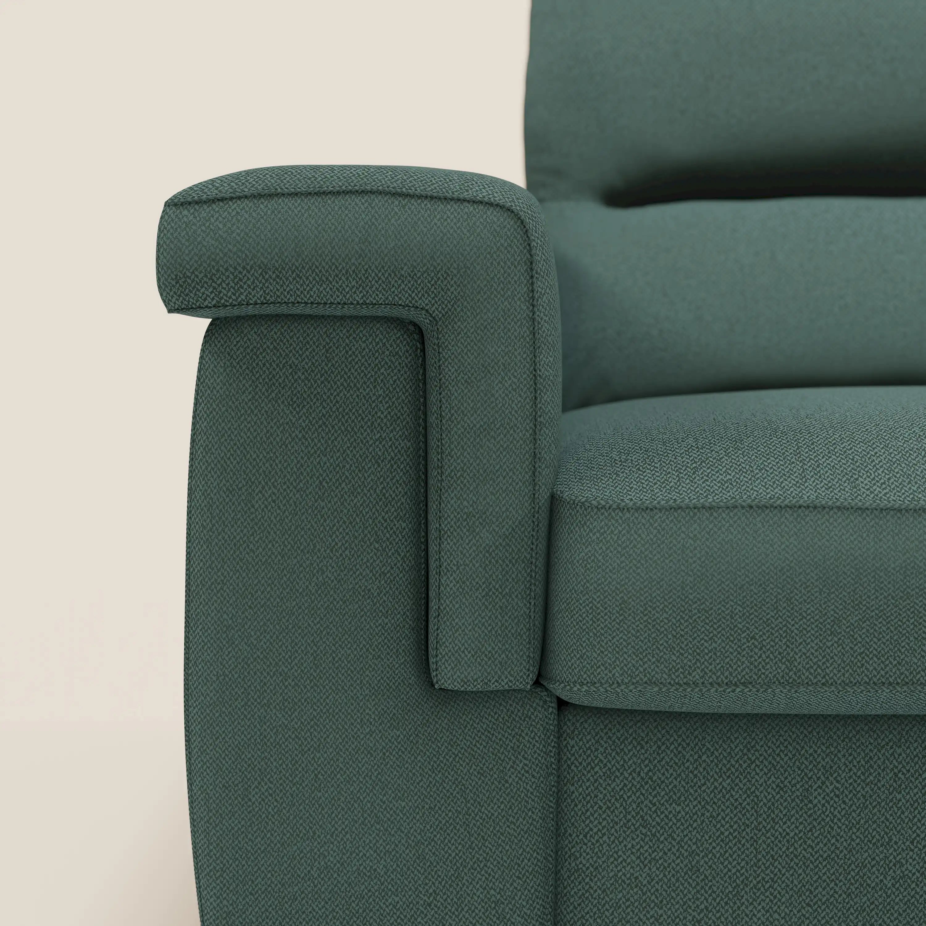 Primo piano del bracciolo sinistro e della seduta del divano letto angolare Magnolia con Penisola Contenitore di Divani.Store in tessuto smacchiabile T05 verde. Lo sfondo beige chiaro ne evidenzia le linee pulite e il design moderno e ammortizzato.