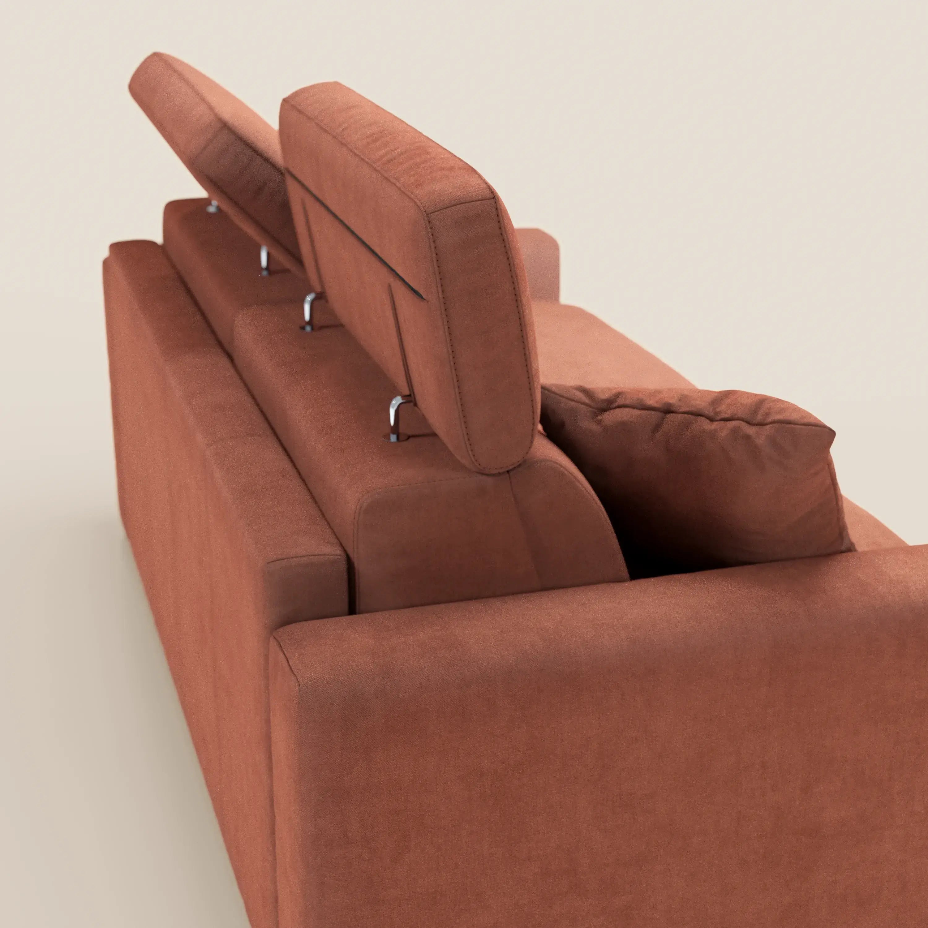 Il divano letto a 3 posti Maximus di Divani.Store è raffigurato nella vista posteriore, rivestito in tessuto color ruggine, resistente alle macchie e certificato Oeko-Tex. Due poggiatesta regolabili sono sollevati con i supporti a vista; uno rimane disteso. Sul sedile è appoggiato un cuscino decorativo coordinato. Sfondo beige chiaro.