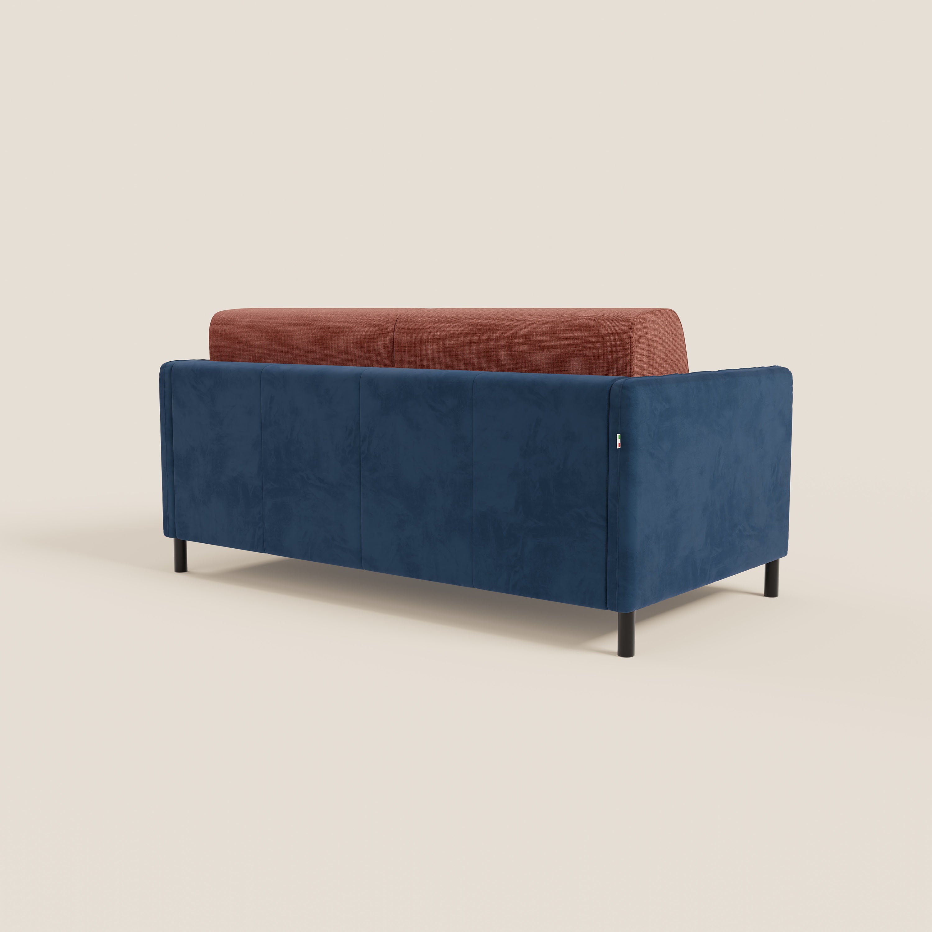 Il divano letto Narciso di Divani.Store è caratterizzato da una base in microfibra lavabile di colore blu intenso, inserti in tessuto impermeabile rosso ruggine (corallo), gambe nere e un design minimale e contemporaneo, visto da dietro su uno sfondo chiaro.
