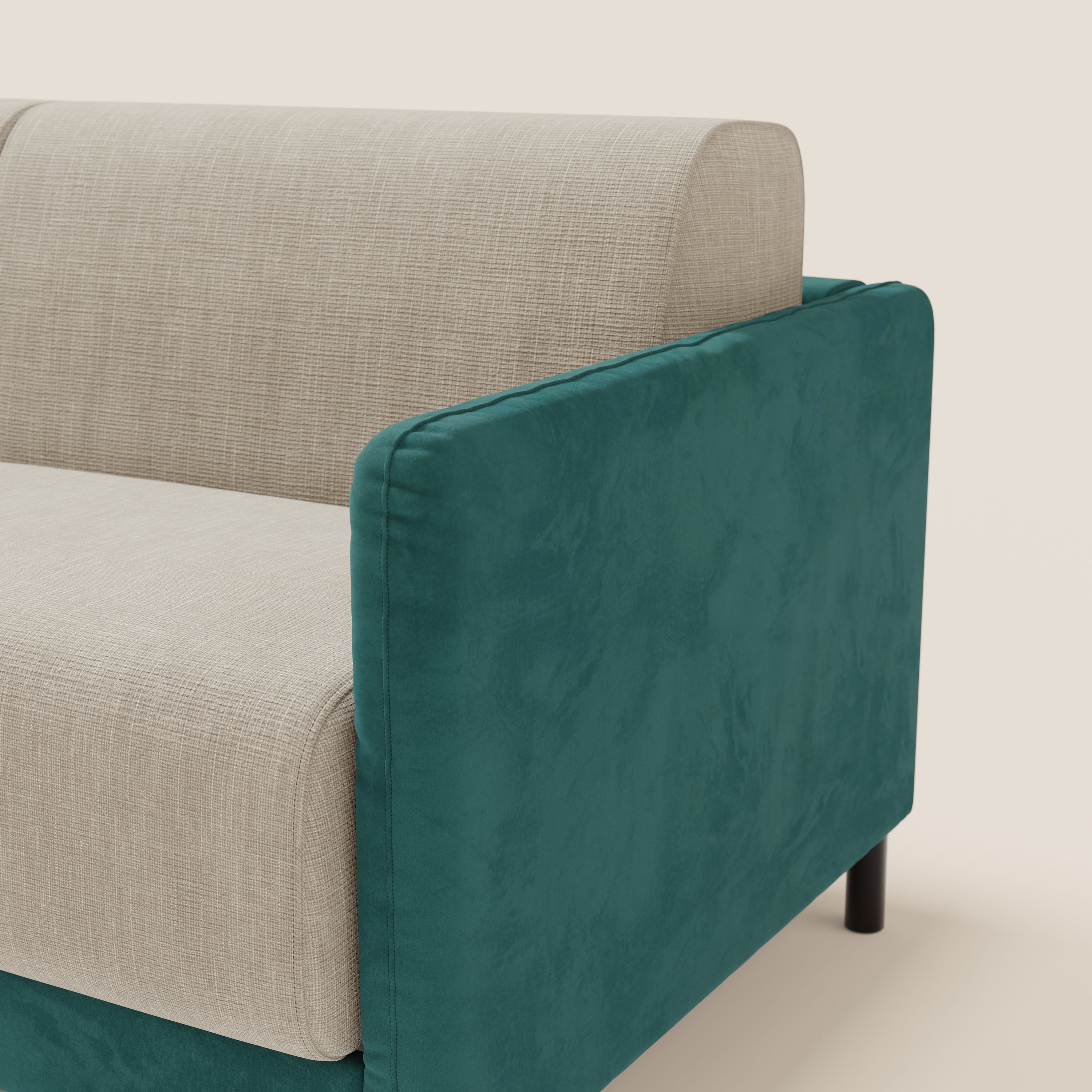 Un primo piano del divano letto Narciso di Divani.Store mostra il rivestimento bicolore petrolio-panna in microfibra antimacchia e tessuto impermeabile T06, il bracciolo in tessuto felpato e le gambe corte nere su uno sfondo bianco sporco.