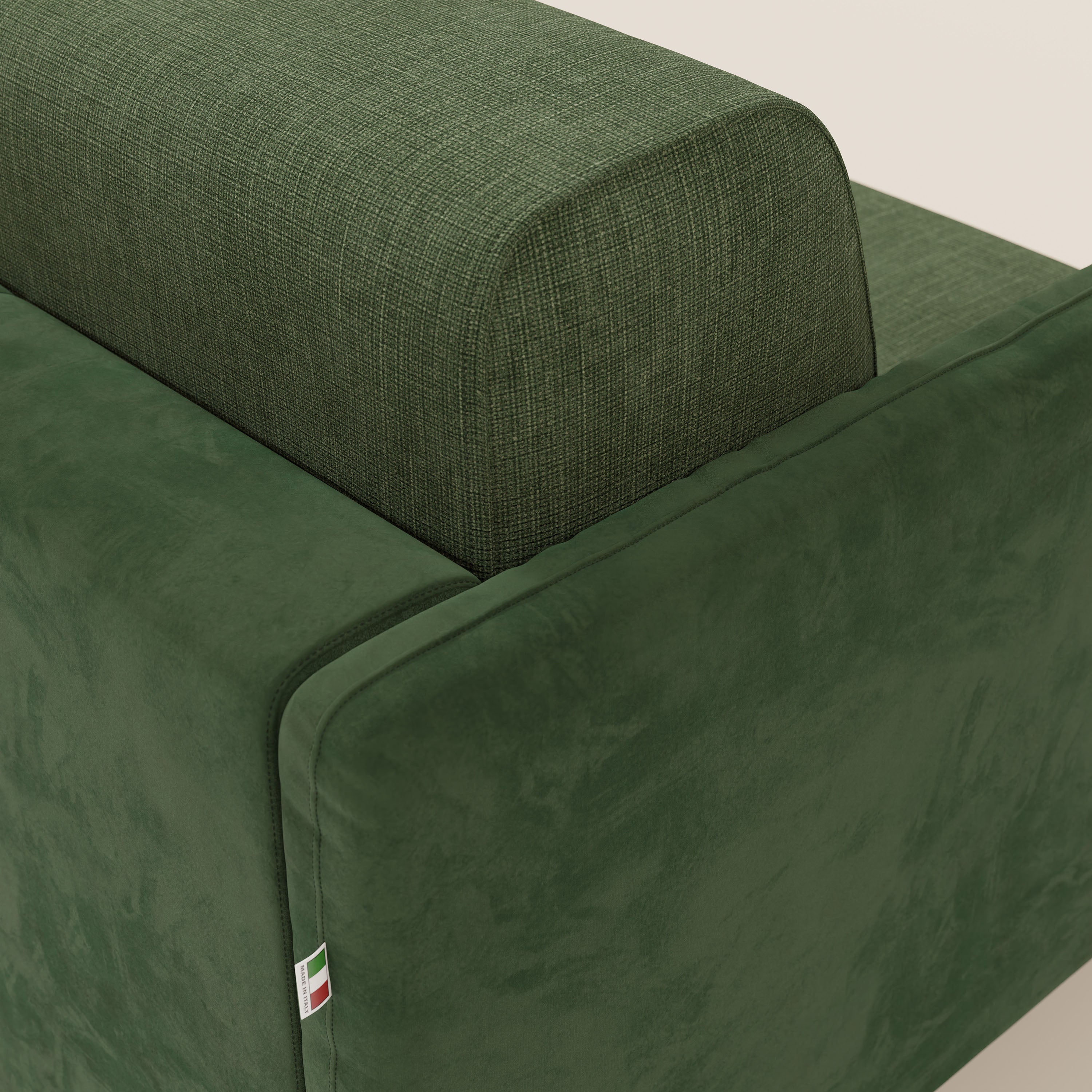 Primo piano del divano letto Narciso di Divani.Store: design bicolore verde con tessuto impermeabile T06 testurizzato e microfibra liscia antimacchia, con etichetta della bandiera italiana sulla cucitura. Fondo chiaro a tinta unita.