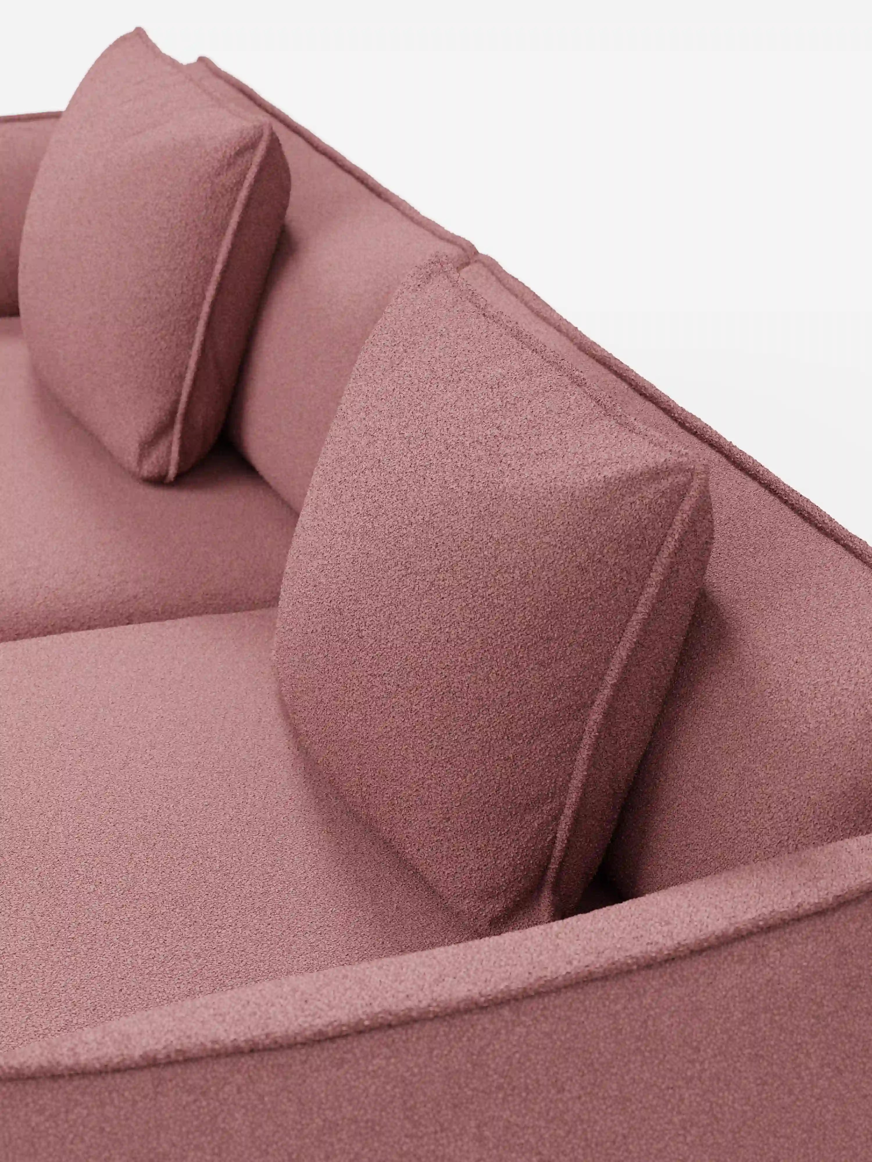 Un primo piano del divano Nimbus a 3 posti, modulare e componibile da 250 cm di Divani.Store, presenta un rivestimento in tessuto T33 antimacchia color rosa polveroso con effetto cotone. Due cuscini quadrati coordinati per lo schienale e una seduta imbottita accentuano il design moderno, con il tessuto testurizzato che risalta su uno sfondo bianco luminoso.