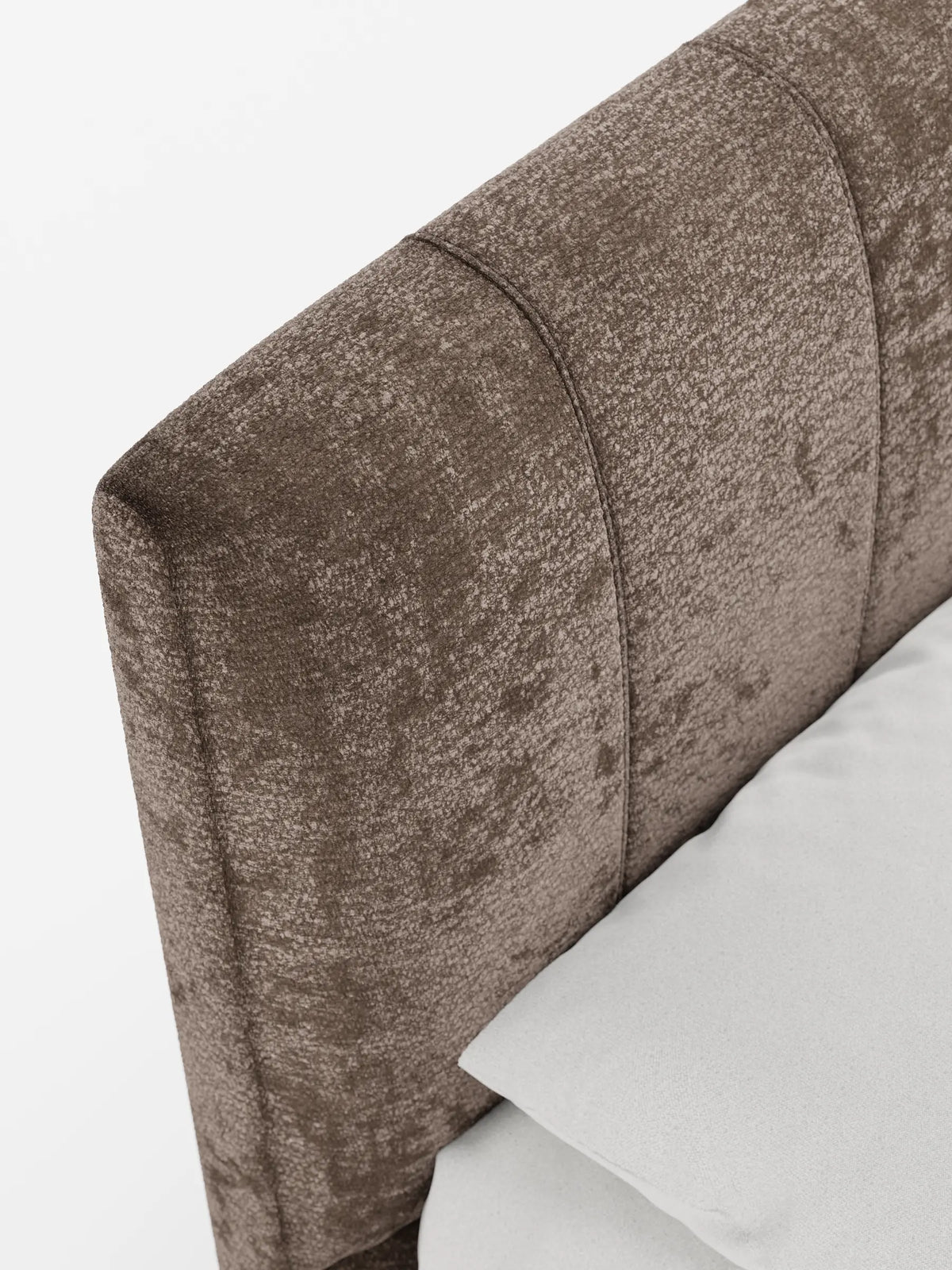 Un primo piano del letto imbottito ONYX con contenitore e testiera verticale in tessuto certificato Oeko-Tex®, caratterizzato da una testiera in tessuto marrone scuro con cuciture verticali e un morbido cuscino grigio chiaro su uno sfondo bianco a tinta unita.