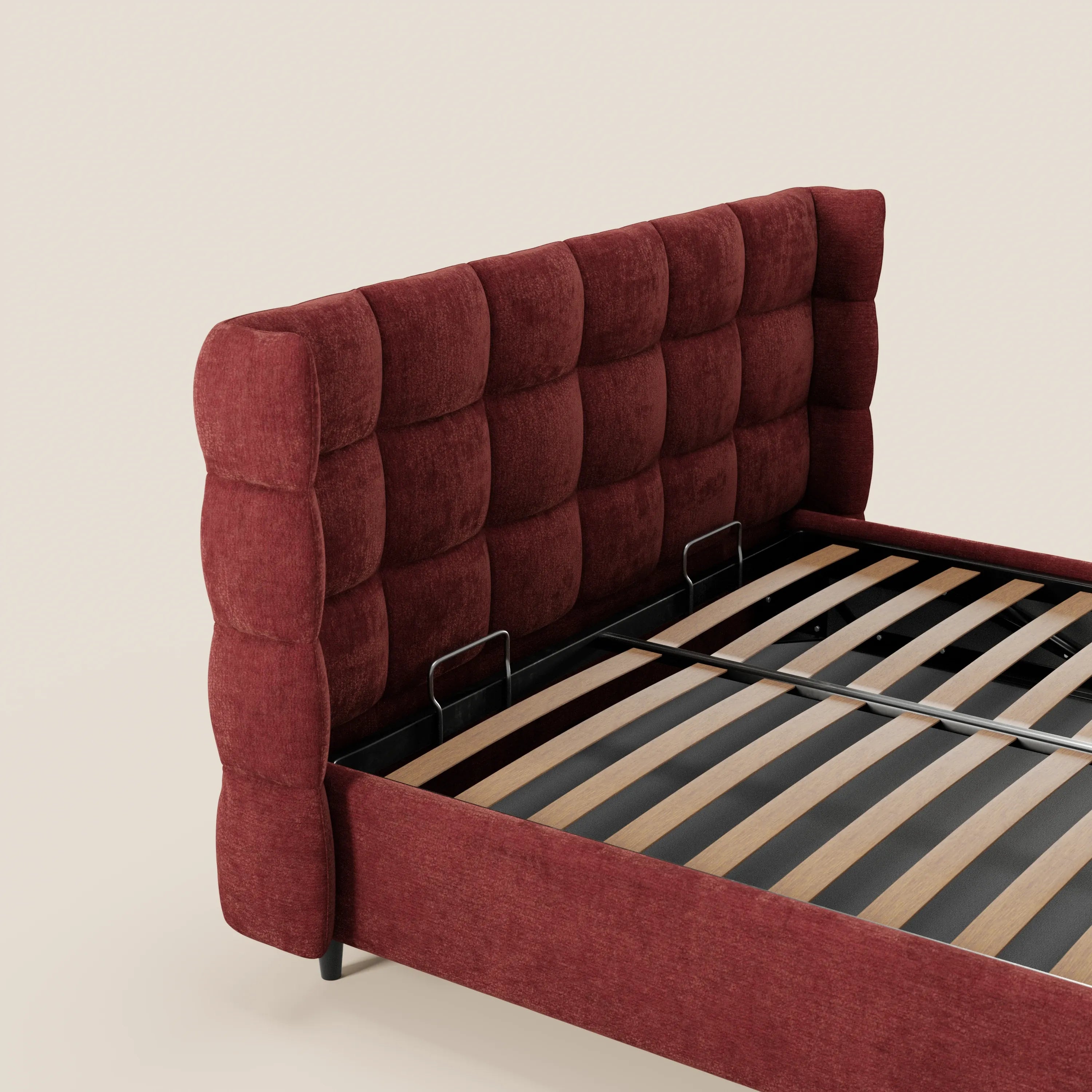 Il letto imbottito RAGNAR di Letti.store presenta una testiera alta capitonné in un elegante tessuto rosso intenso certificato Oeko-Tex®, una struttura imbottita abbinata con contenitore, doghe in legno, supporti in metallo nero e uno sfondo bianco sporco.