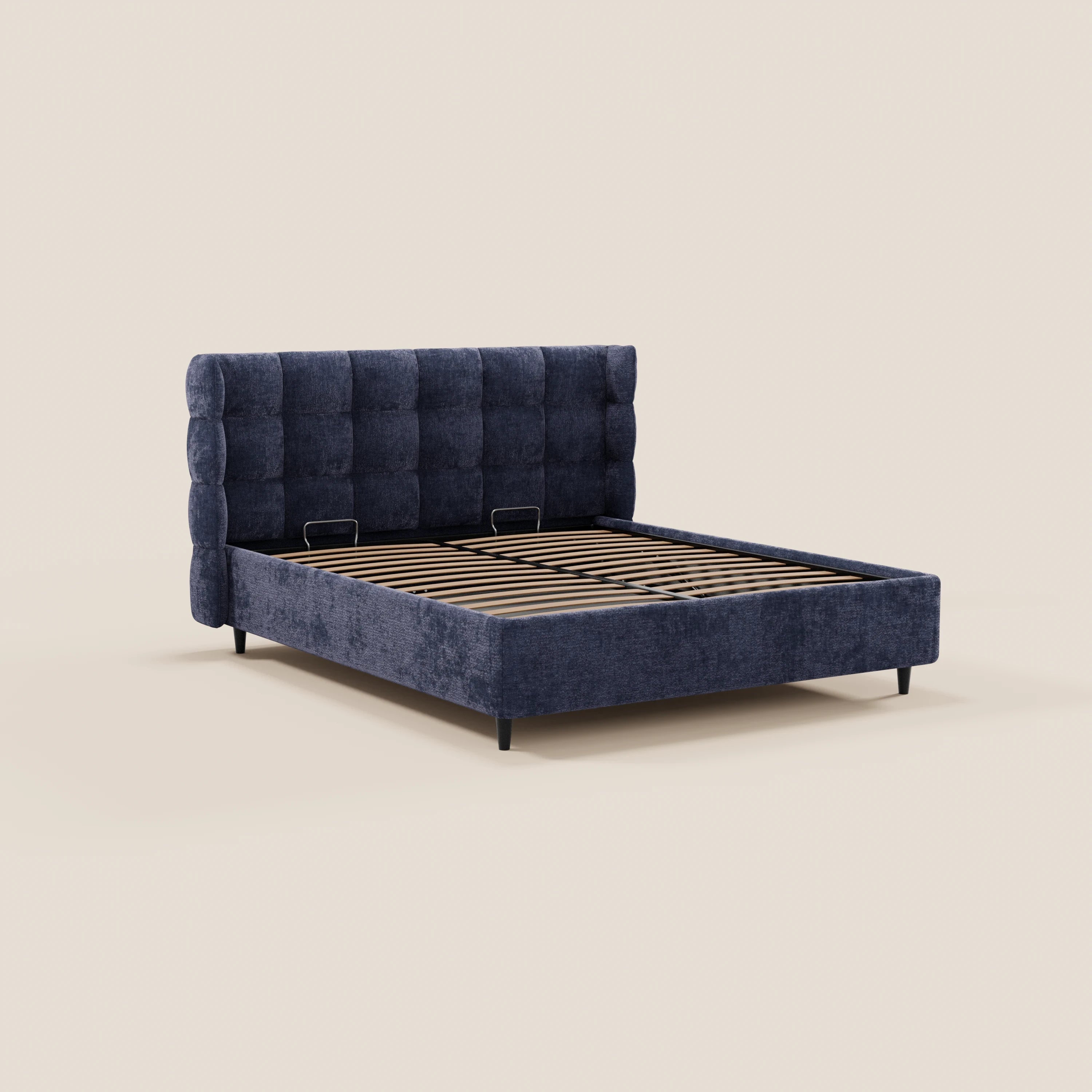 Il letto imbottito RAGNAR di Letti.store presenta una testiera alta e capitonné in un elegante tessuto certificato Oeko-Tex®, sponde laterali e pediera in tinta, doghe in legno e gambe corte nere, il tutto su uno sfondo beige chiaro a tinta unita.