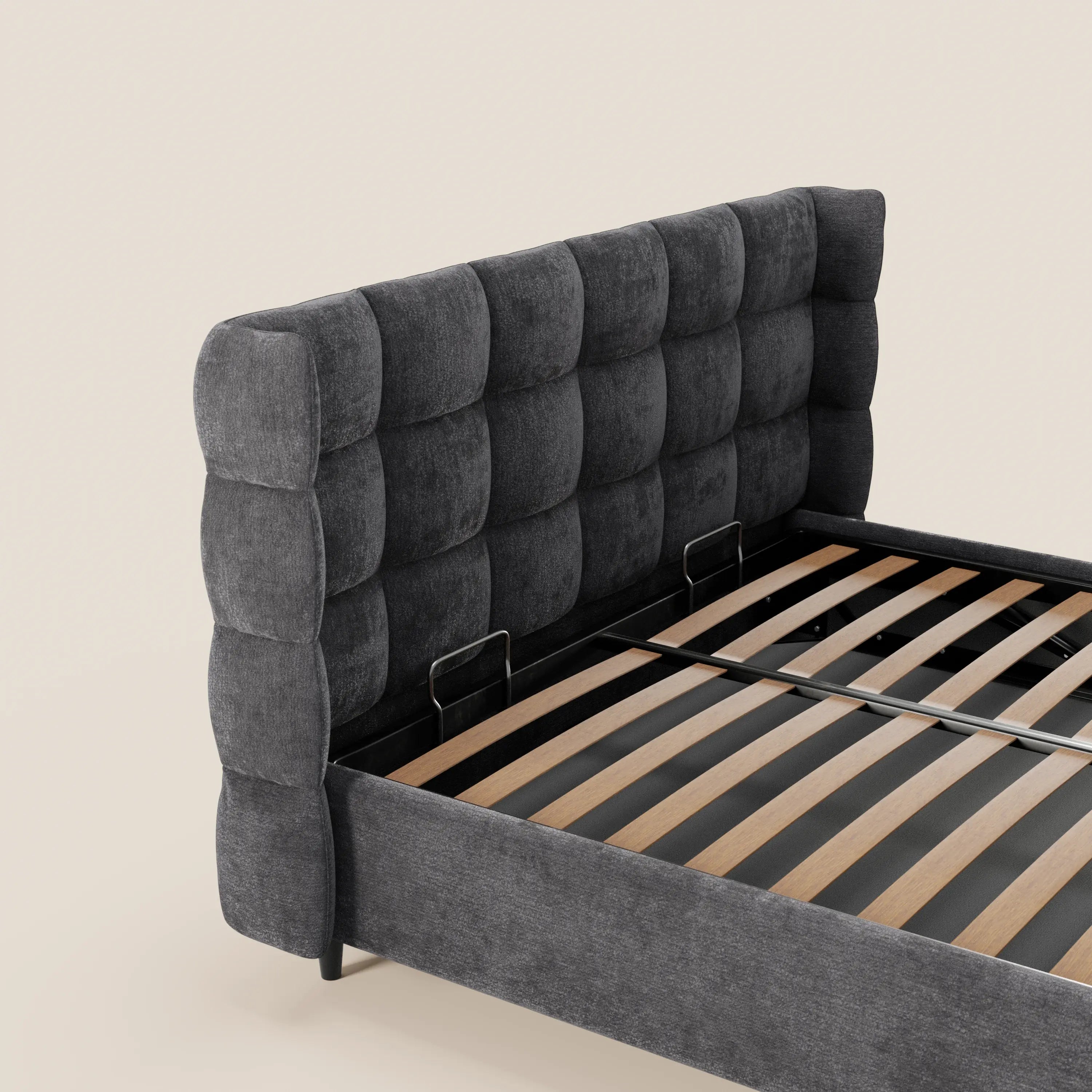 Il letto imbottito RAGNAR di Letti.store presenta una testiera capitonné avvolgente in tessuto Oeko-Tex®. È dotato di vano contenitore, doghe in legno e linee minimal su uno sfondo beige chiaro. Materasso escluso.