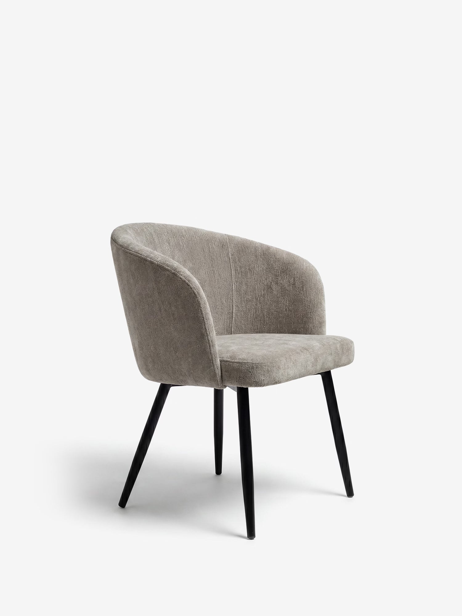 La sedia Rovo con braccioli di Divani.Store presenta uno schienale e braccioli curvi, imbottiti e rivestiti in morbida ciniglia. Le sue quattro gambe angolate in metallo nero conferiscono alla sedia un aspetto elegante e moderno sullo sfondo bianco a tinta unita.