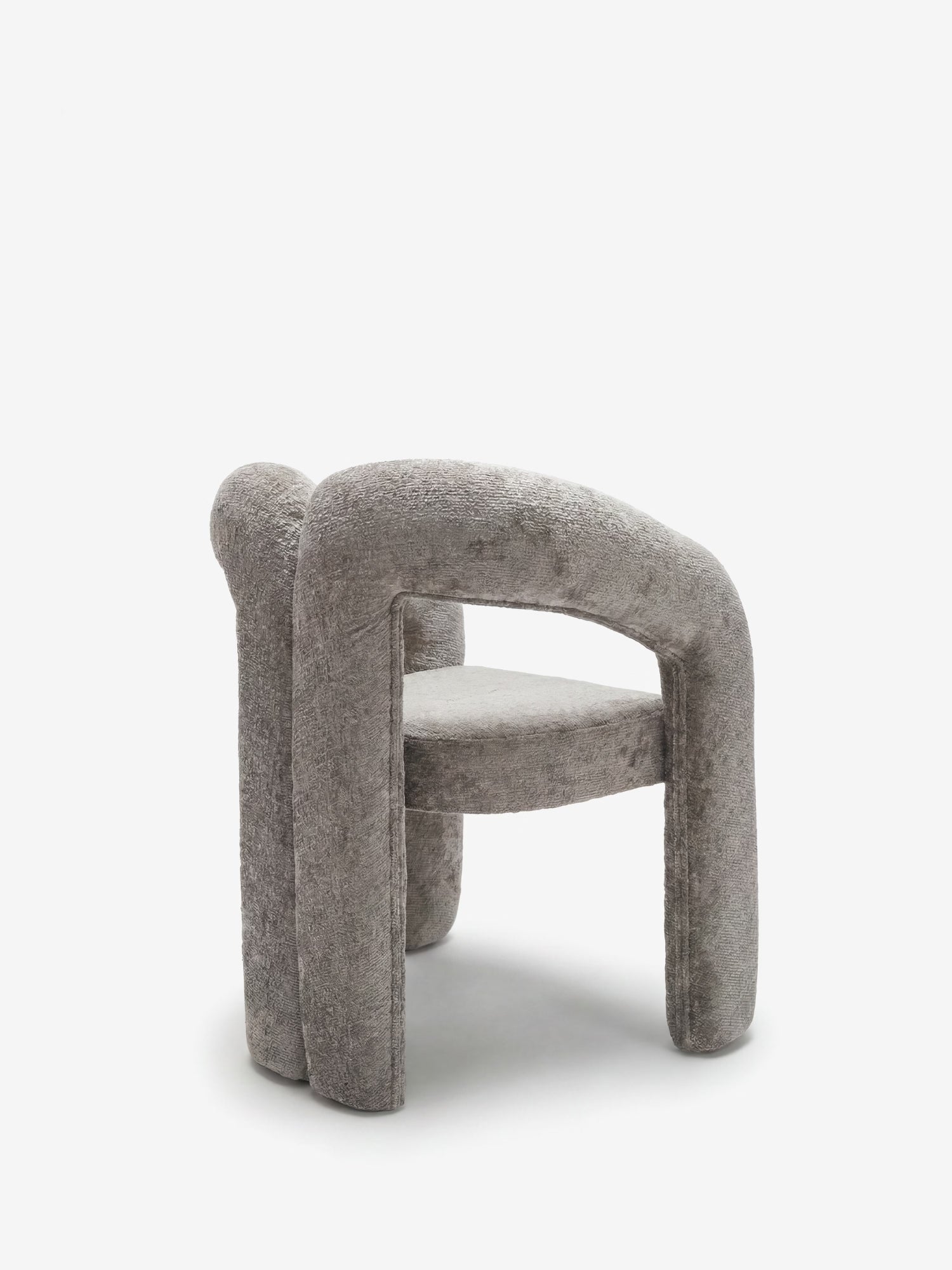 La sedia di design Sibilla di Divani.Store presenta una forma arcuata interamente imbottita, con un'imbottitura spessa e arrotondata e tre gambe cilindriche: un'elegante sedia contemporanea rivestita in morbido tessuto grigio chiaro.