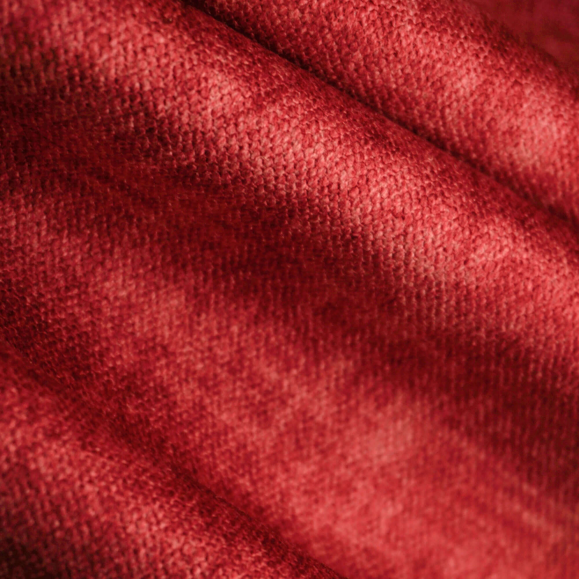 Primo piano di T35 SOFIA di Divani.Store: un velluto nuvolato rosso con trama a vista. Morbide ombre evidenziano le sue pieghe morbide e il colore ricco, mettendo in evidenza questo elegante, smacchiabile e impermeabile tessuto Easy Clean.