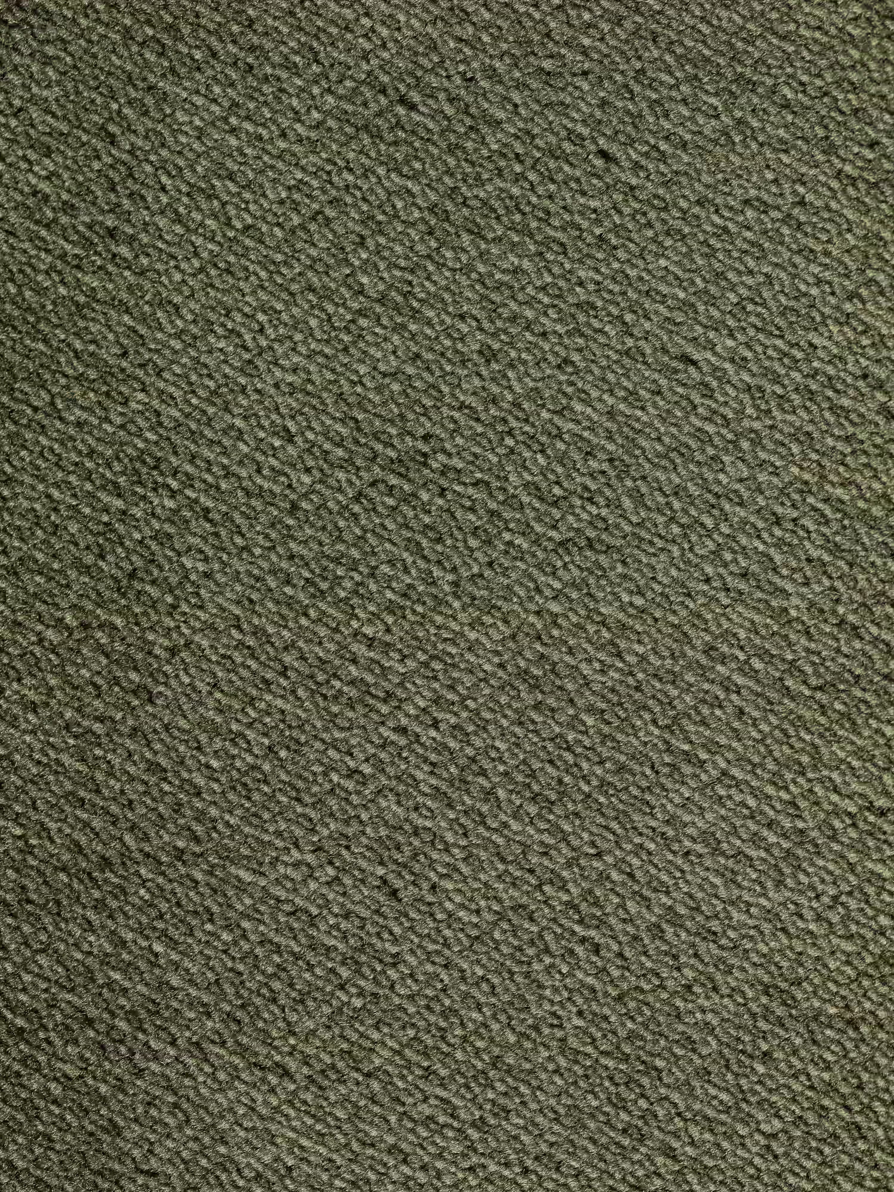 Primo piano del tessuto T30 smacchiabile, di colore verde oliva e dalla trama ruvida, caratterizzato da un delicato motivo a trama diagonale; una cucitura a vista attraversa orizzontalmente la superficie, interrompendo delicatamente l’aspetto altrimenti uniforme: un dettaglio elegante che caratterizza il divano Michelangelo a 2 e 3 posti con sedute allungabili e poggiatesta reclinabili di Divani.Store.