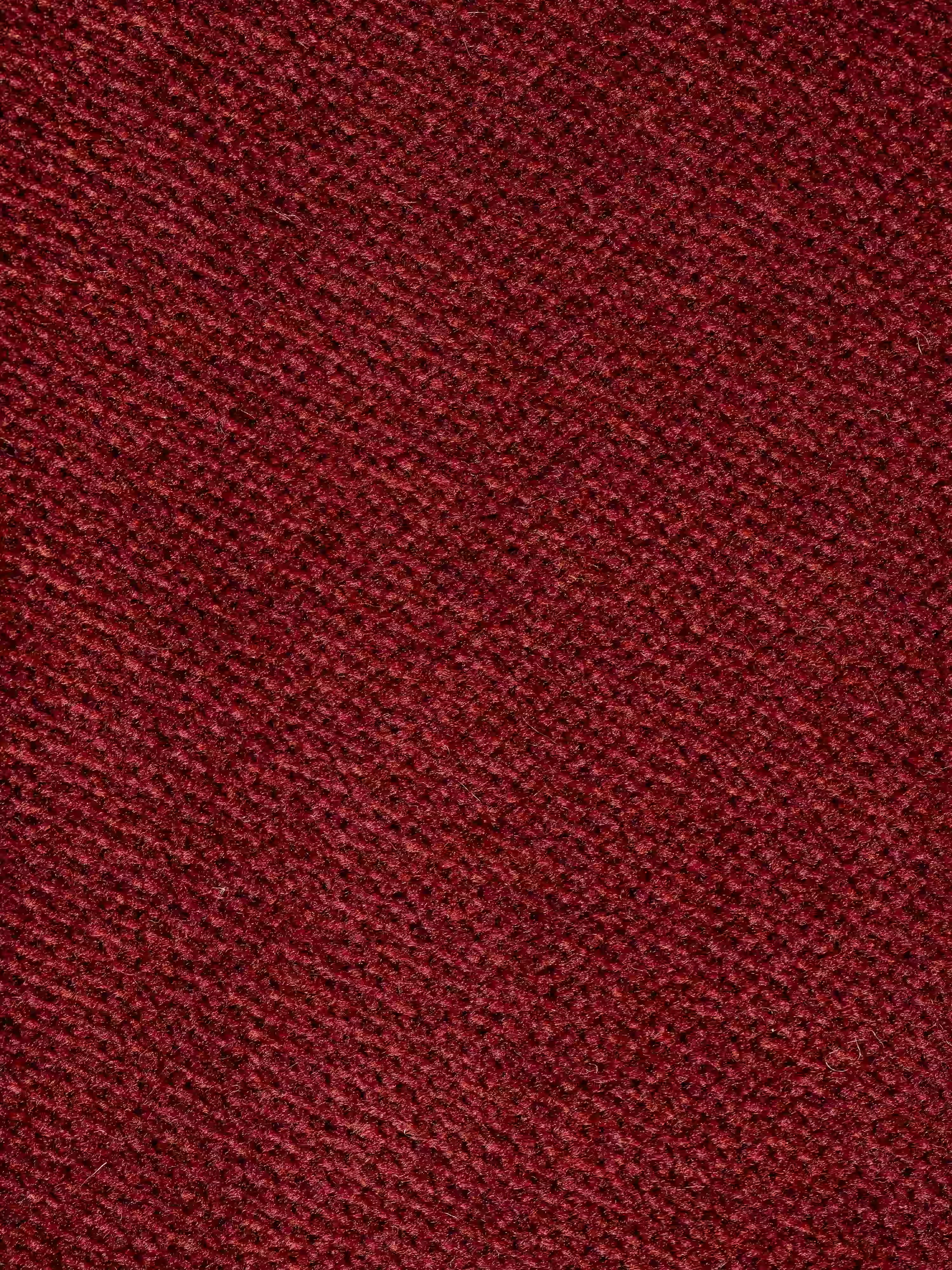 Primo piano su un tessuto rosso dalla trama ruvida con motivo a trama diagonale, come quello presente sul divano Michelangelo a 2 e 3 posti con sedute allungabili e poggiatesta reclinabili in tessuto smacchiabile T30 di Divani.Store. Il materiale appare morbido e spesso, creando un senso di profondità e sottili sfumature su tutta la superficie. È visibile solo la ricca trama del tessuto, ideale per il rivestimento di divani moderni con sedute allungabili.