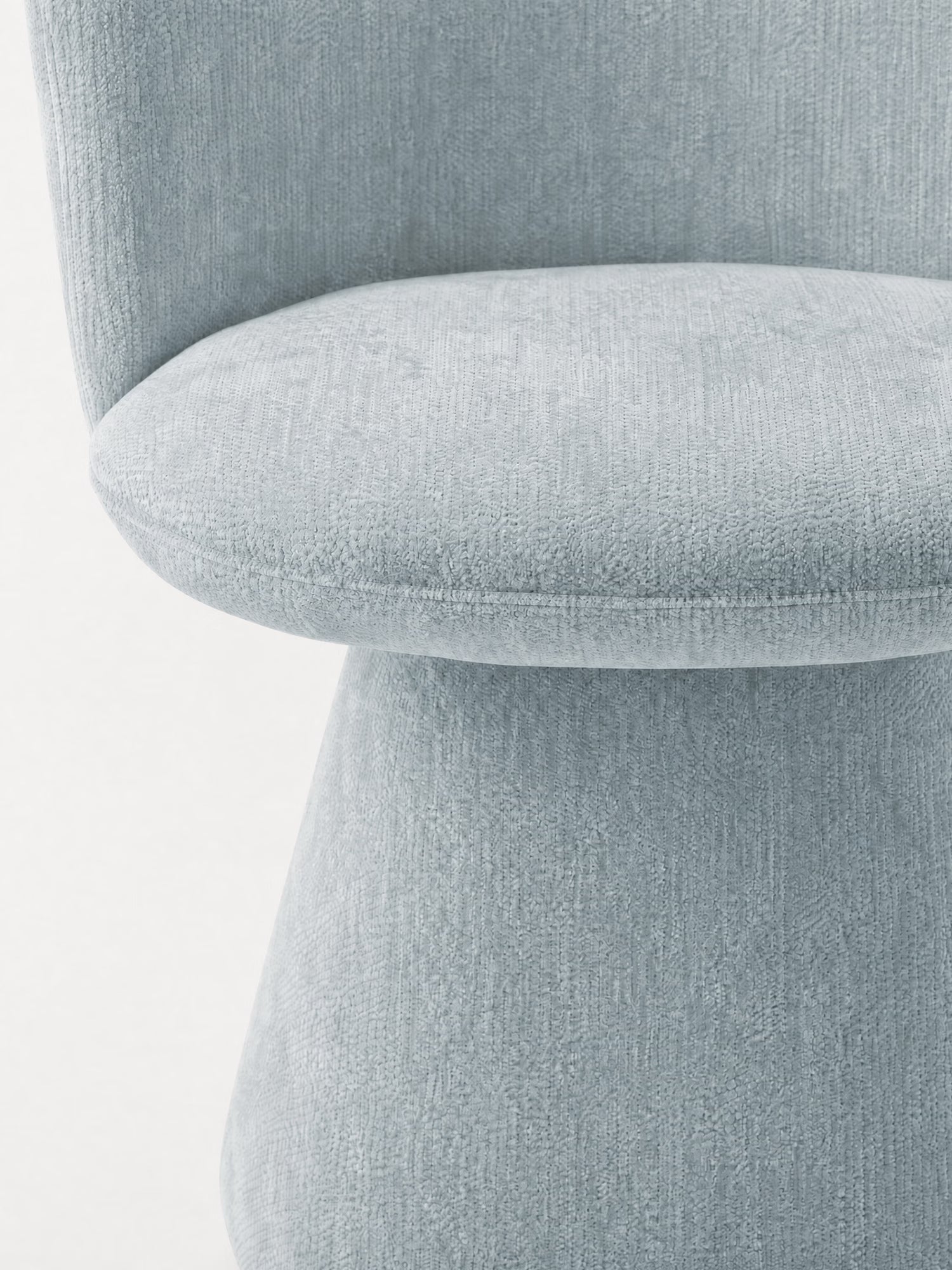 Primo piano della sedia moderna imbottita Talia di Divani.Store, rivestita in ciniglia grigio chiaro certificata OEKO-TEX®. L'immagine mette in risalto la seduta curva, lo schienale arrotondato e lo stile minimalista e lineare su uno sfondo bianco uniforme.