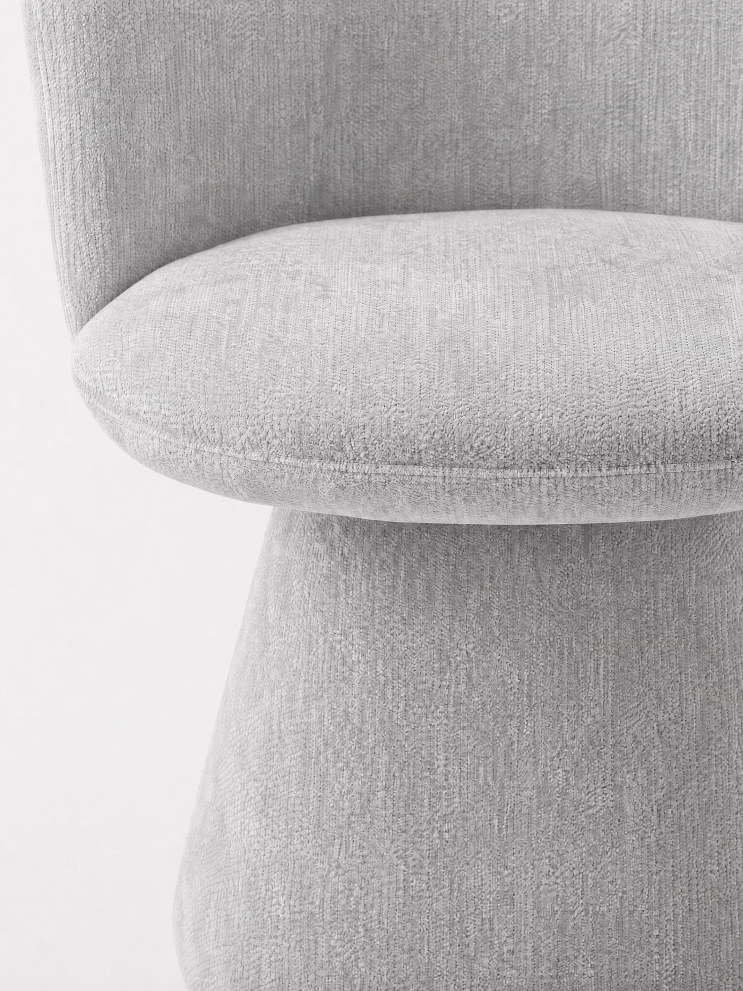 Primo piano della sedia moderna Talia di Divani.Store, rivestita in morbido tessuto ciniglia OEKO-TEX® color grigio chiaro. Lo schienale curvo e la seduta arrotondata ne esaltano le linee morbide, la texture delicata e il design minimalista, con una base imbottita in tinta.