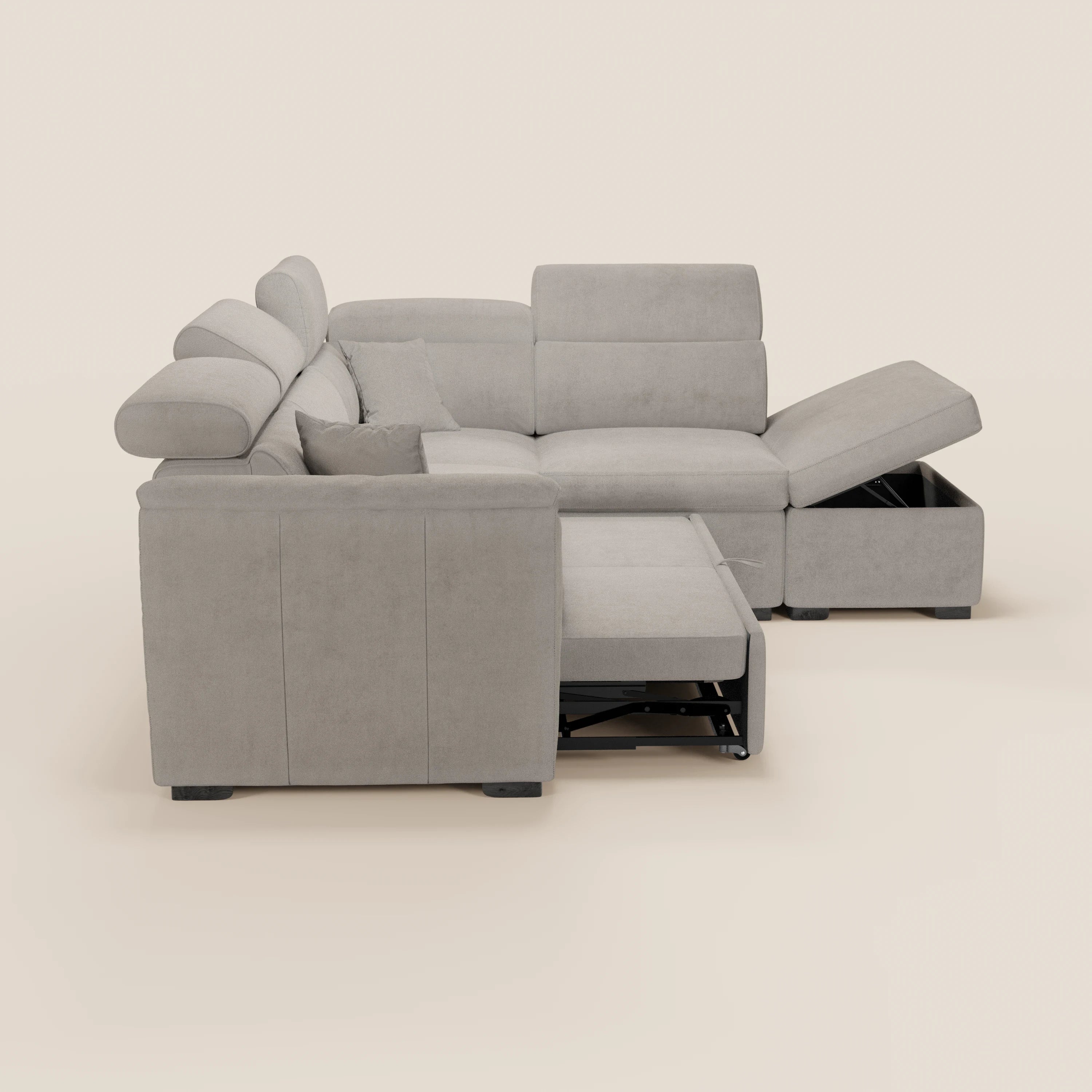 Il divano angolare reversibile Titano di Divani.Store è dotato di poggiatesta regolabili, un poggiapiedi estraibile, un pouf contenitore con coperchio apribile e un cuscino coordinato in tessuto grigio chiaro Smacchiabile Oeko-Tex®, su sfondo beige.