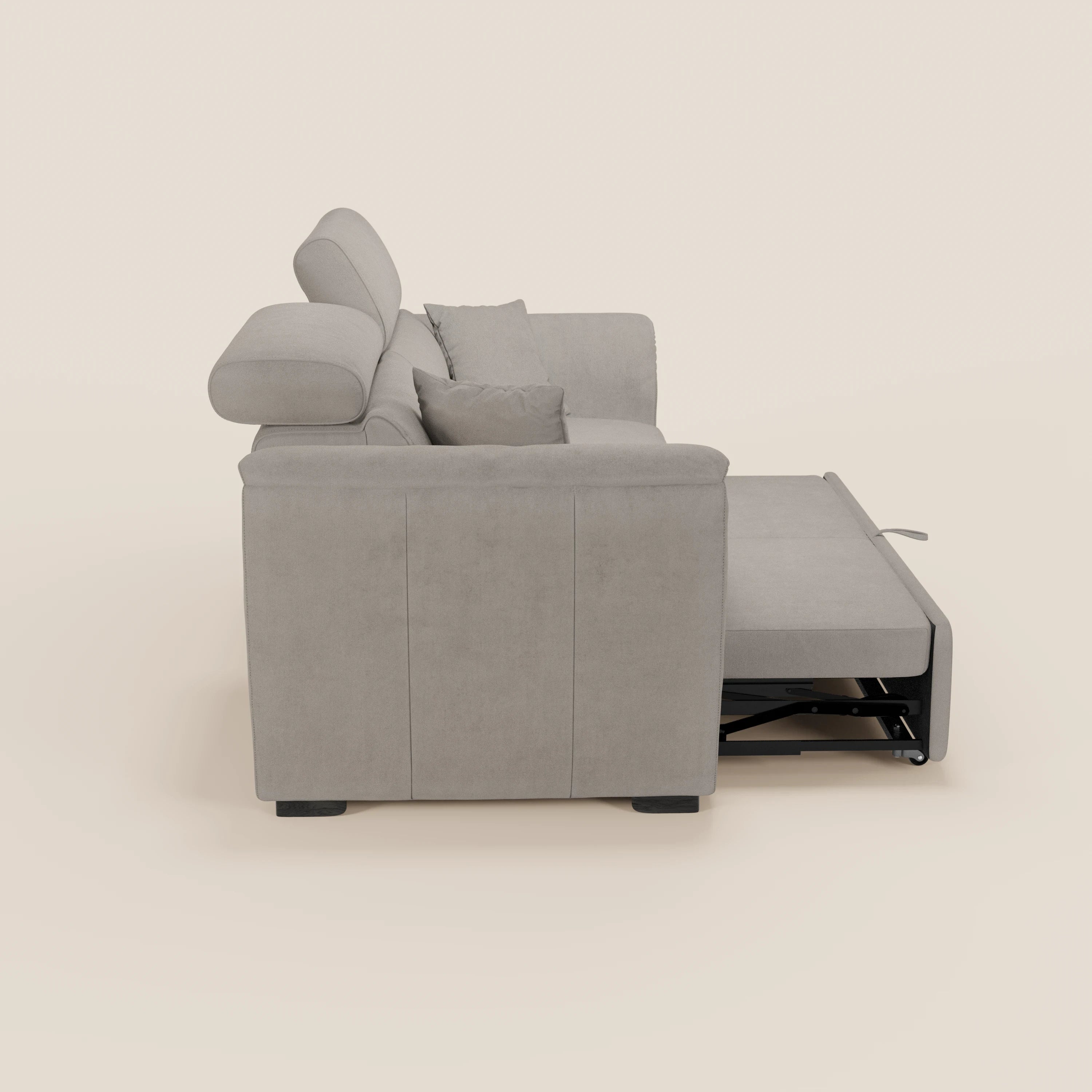 Vista laterale del divano a 2 posti estraibile Titano di Divani.Store, in tessuto smacchiabile Oeko-Tex® grigio chiaro, dotato di poggiatesta reclinabili, braccioli, sezione letto estraibile e due cuscini coordinati su sfondo beige.