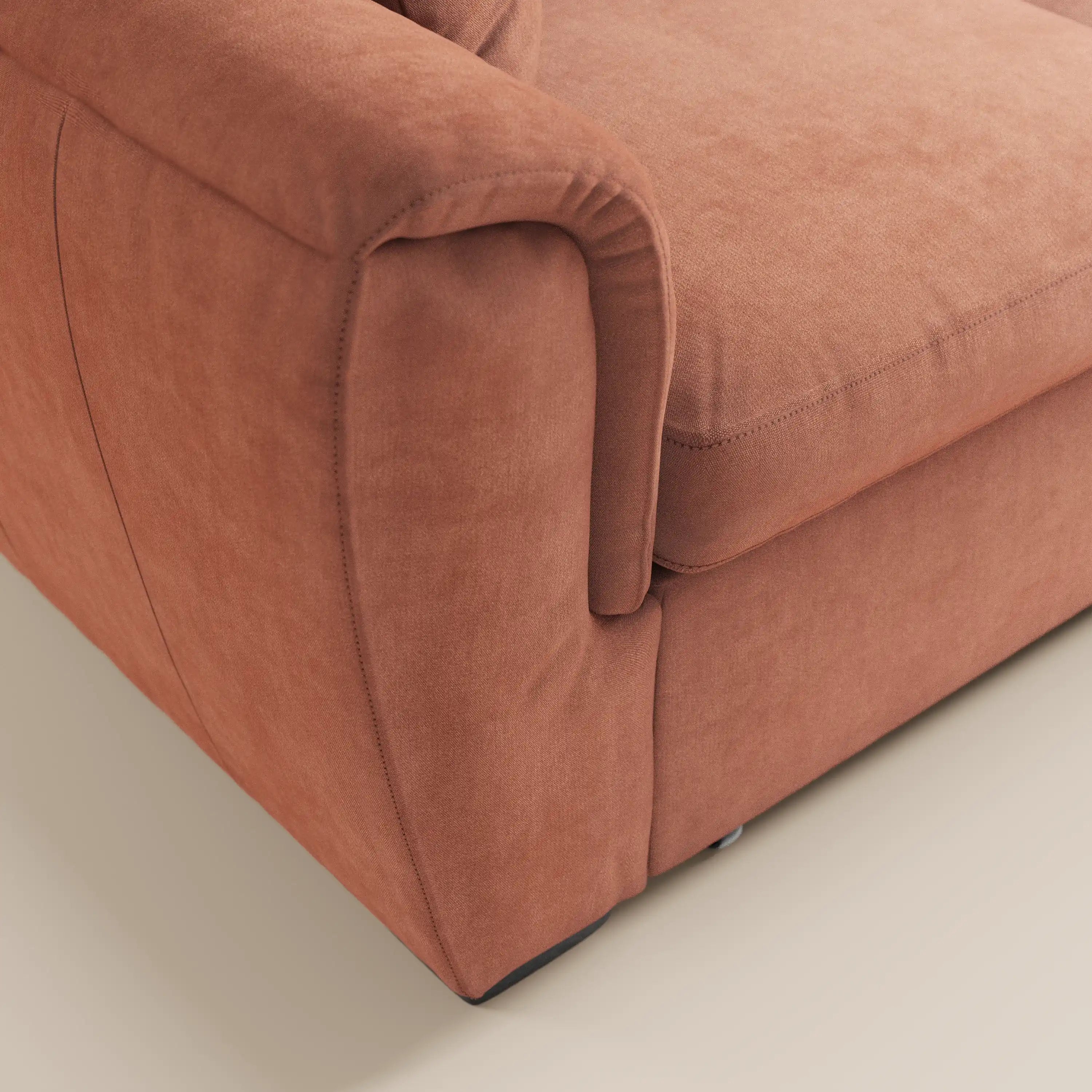 Primo piano del divano a 2 posti estraibile Titano di Divani.Store, realizzato in morbido tessuto color ruggine certificato Oeko-Tex® e resistente alle macchie, con braccioli arrotondati e poggiatesta reclinabili: perfetto per gli ambienti moderni.