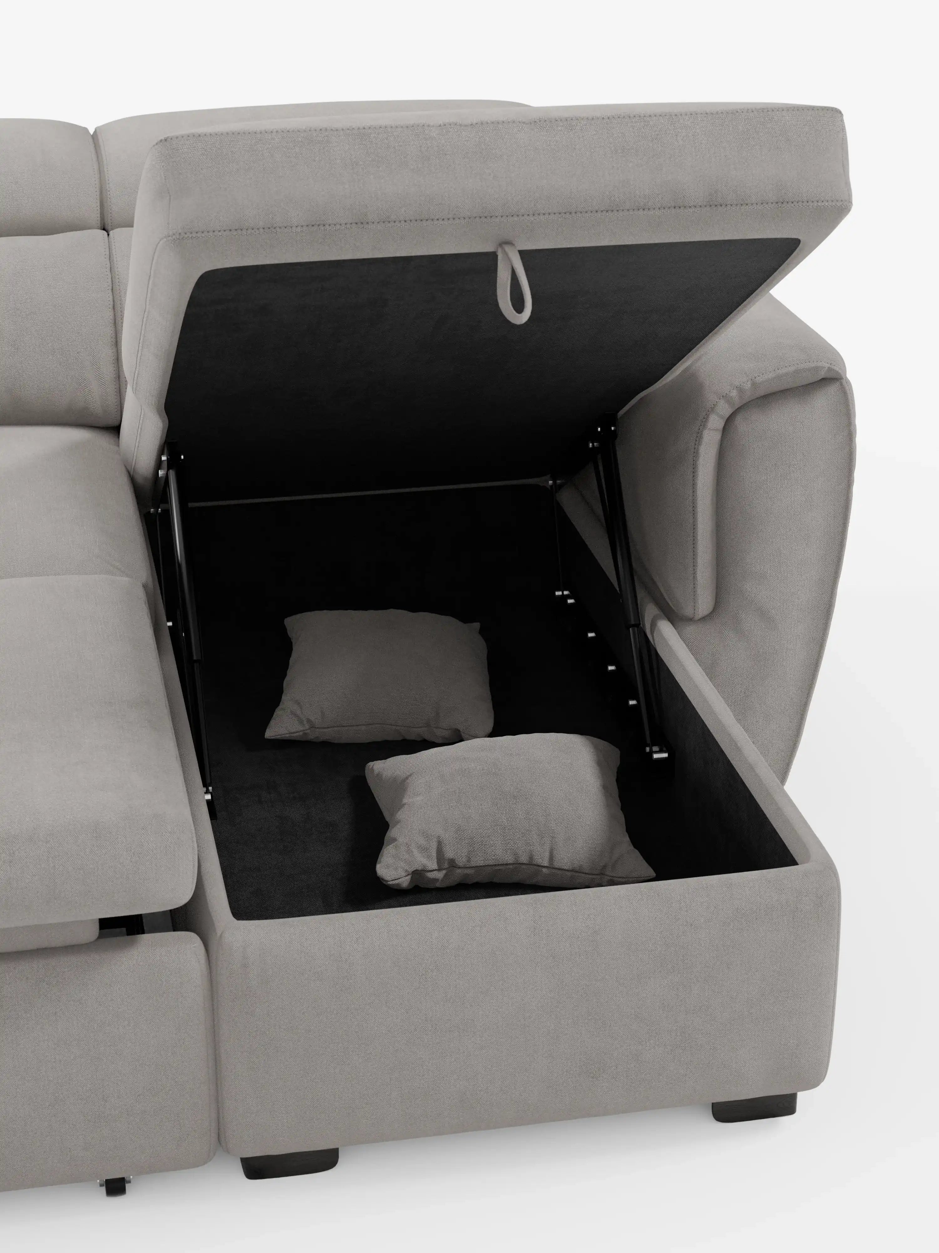 Un divano letto Titano grigio chiaro con penisola reversibile e contenitore di Divani.Store è raffigurato su uno sfondo bianco. Questo moderno divano componibile presenta un vano portaoggetti aperto sotto una delle sedute, che contiene due cuscini grigi abbinati, con il coperchio sostenuto da cerniere metalliche. Il divano presenta gambe corte nere e include poggiatesta reclinabili e un elemento estraibile, il tutto rivestito in tessuto antimacchia.