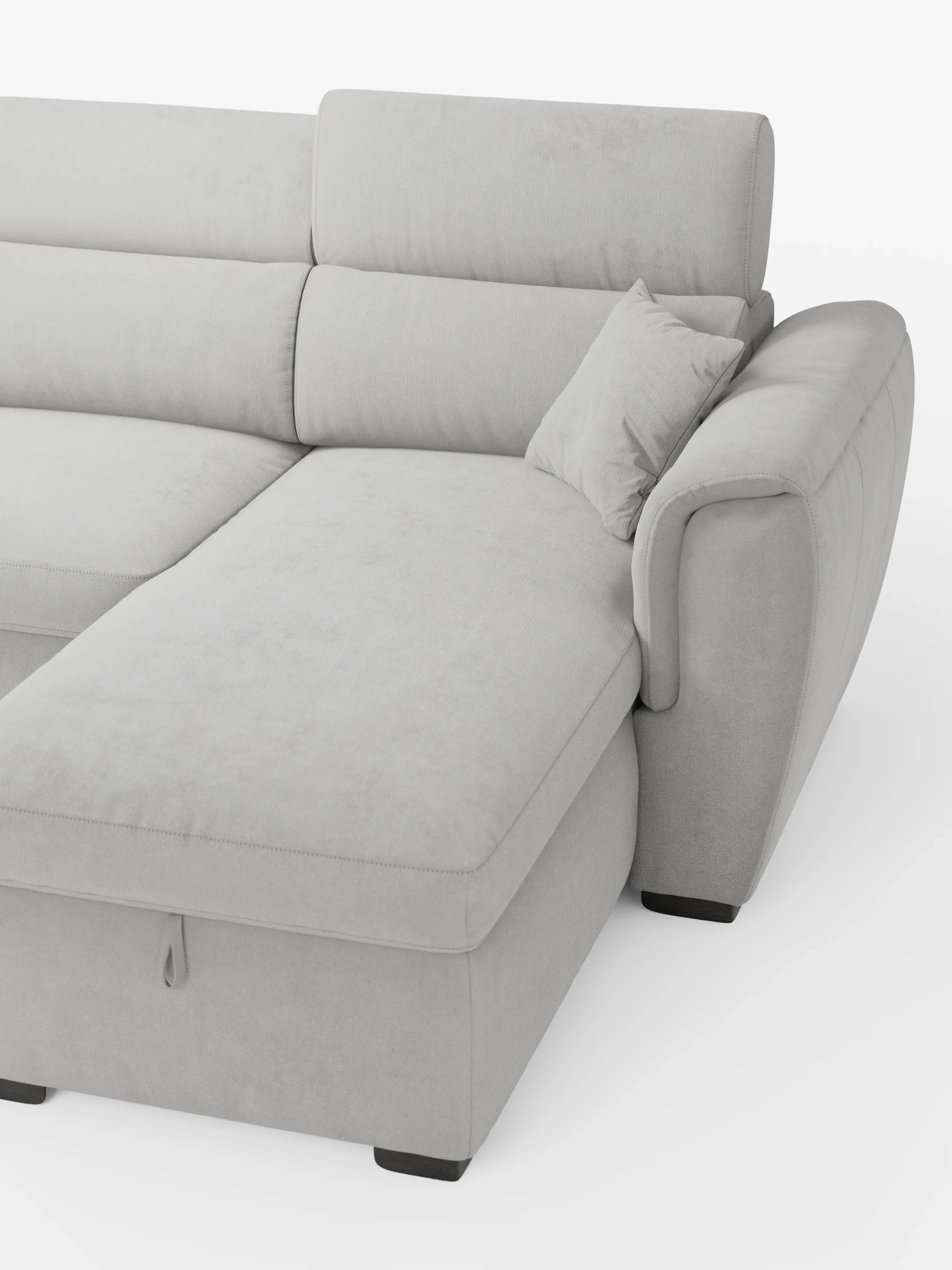 Il divano letto Titano con penisola reversibile e contenitore di Divani.Store è un divano moderno di colore grigio chiaro, dotato di chaise longue reversibile, poggiatesta reclinabili e un elemento estraibile. Rivestito in tessuto facile da pulire, questo divano contemporaneo presenta ampi cuscini imbottiti, un rivestimento morbido e gambe corte nere. È esposto su uno sfondo bianco.