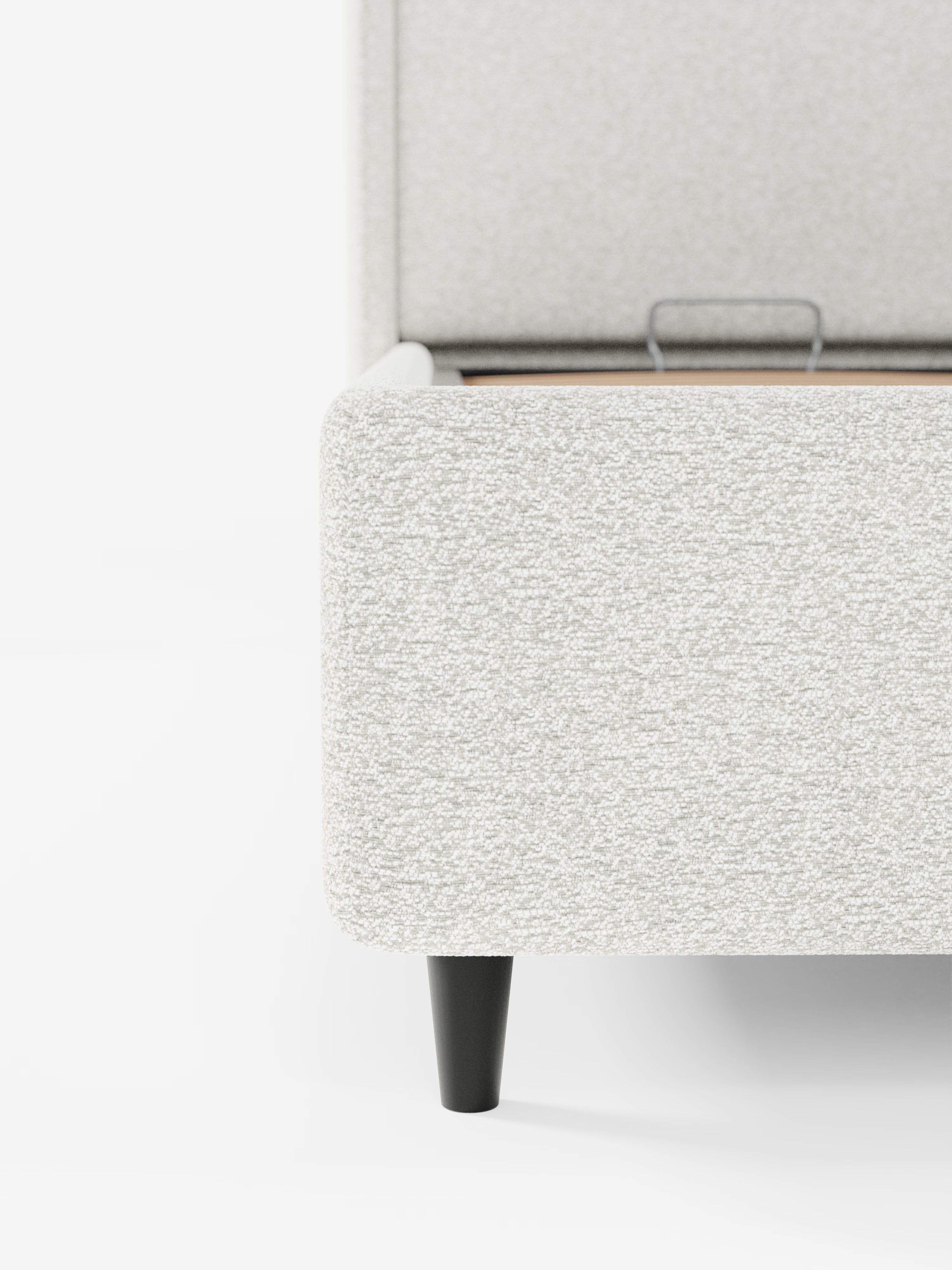 Primo piano del letto di design VALKIRIA con vano contenitore e testiera avvolgente di Letti.store, caratterizzato da un tessuto Oeko-Tex® grigio chiaro con trama in rilievo, un angolo dai bordi dritti e una gamba affusolata nera. Lo sfondo è bianco e lascia intravedere parte della base e della testiera — completa di 2 cuscini imbottiti —, sottolineandone il design contemporaneo.