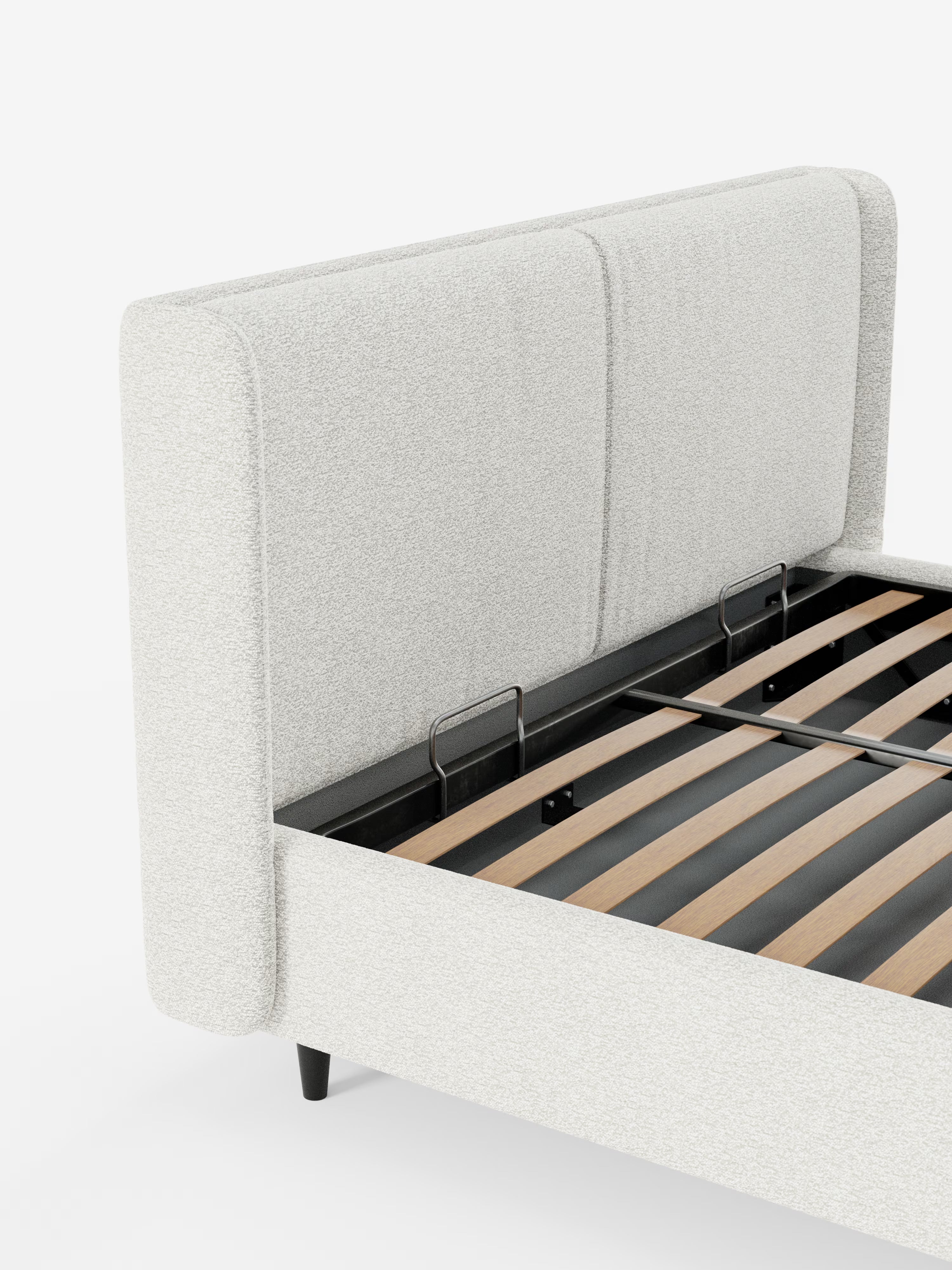 Un primo piano del letto di design VALKIRIA di Letti.store, caratterizzato da una struttura imbottita bianca (letto imbottito) con una testiera alta e avvolgente e due cuscini imbottiti in tessuto Oeko-Tex®. Il design contemporaneo mette in risalto le doghe in legno a vista e una robusta struttura in metallo nero, oltre a un ampio vano contenitore per riporre oggetti sotto il letto. Lo sfondo è bianco a tinta unita.