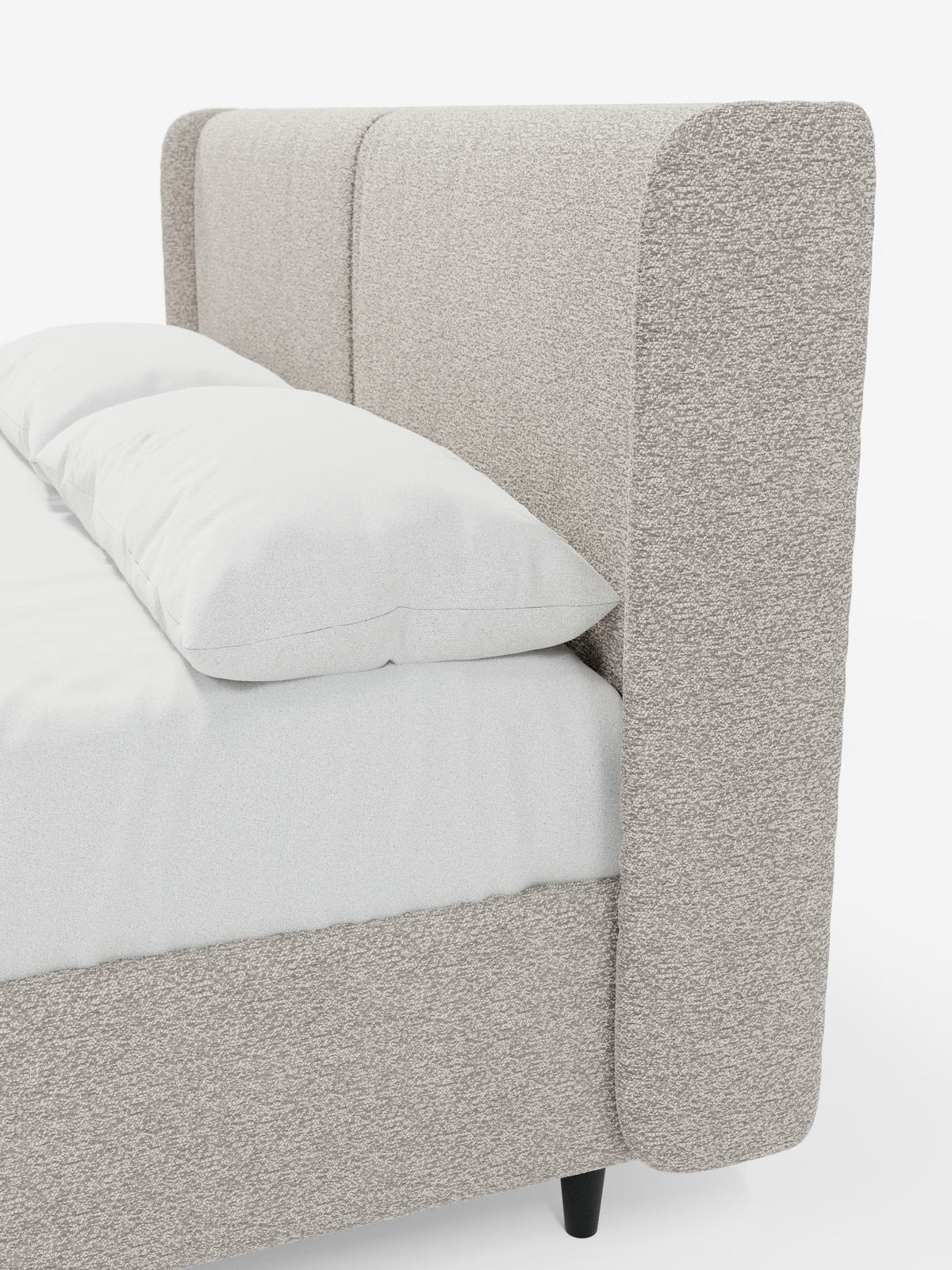 Un primo piano del letto di design VALKIRIA con contenitore e testiera avvolgente di Letti.store ne mette in risalto lo stile contemporaneo, caratterizzato da due cuscini imbottiti e da un rivestimento in tessuto Oeko-Tex® in una tonalità beige neutra. Il letto è vestito con biancheria da letto e cuscini di un bianco candido, poggianti su gambe corte in legno scuro. Fotografato da un’angolazione laterale su uno sfondo bianco a tinta unita, l’immagine mette in risalto l’elegante testiera avvolgente e il
