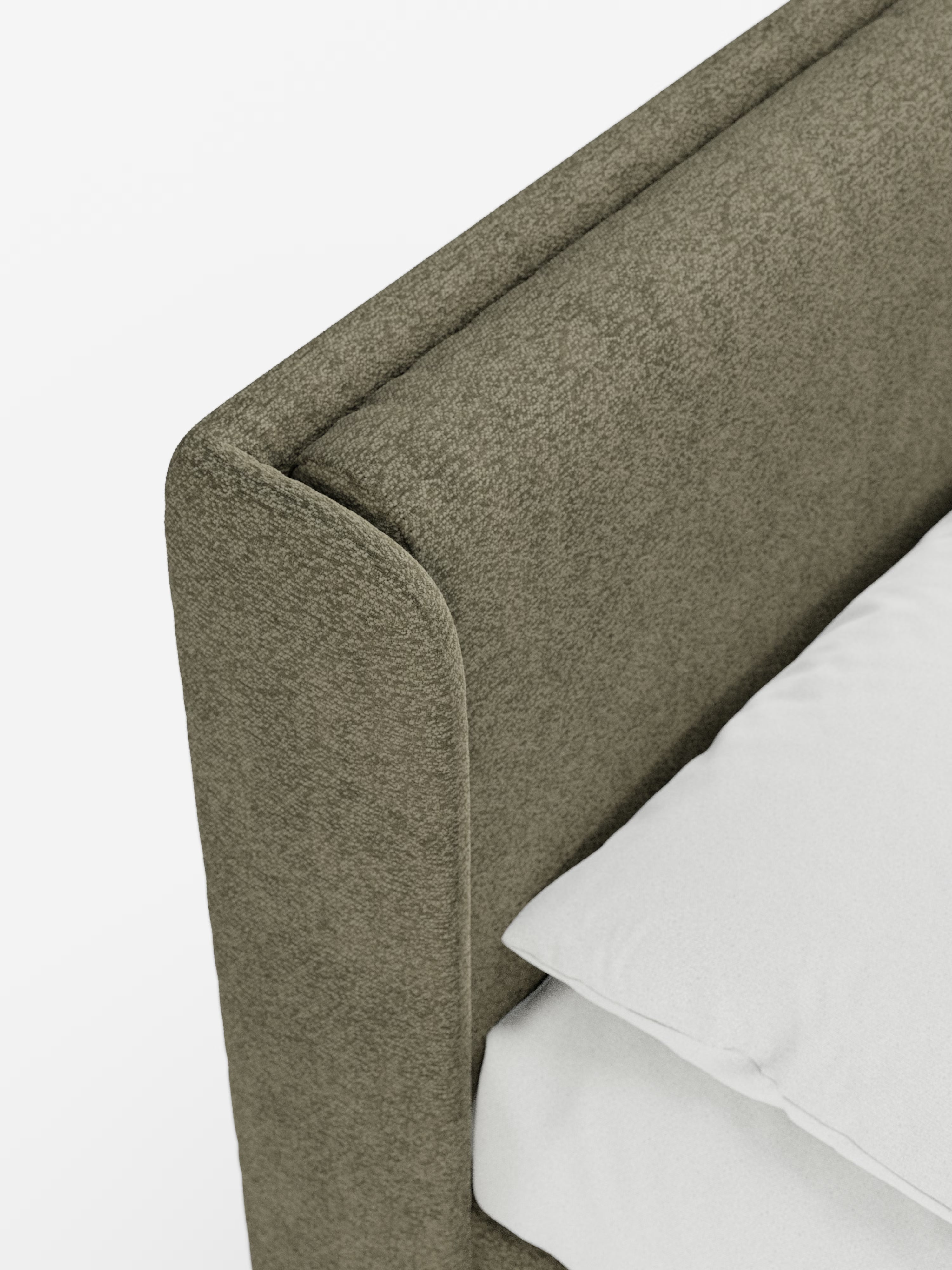Primo piano di un angolo del letto che mette in risalto il “VALKIRIA”, letto di design con vano contenitore e testiera avvolgente di Letti.store, con i suoi due morbidi cuscini in tessuto Oeko-Tex® color verde oliva a trama ruvida. Un cuscino bianco immacolato e un lembo di lenzuolo bianco poggiano sul materasso, mettendo in risalto le linee pulite e i materiali morbidi del letto, per un look moderno e accogliente.