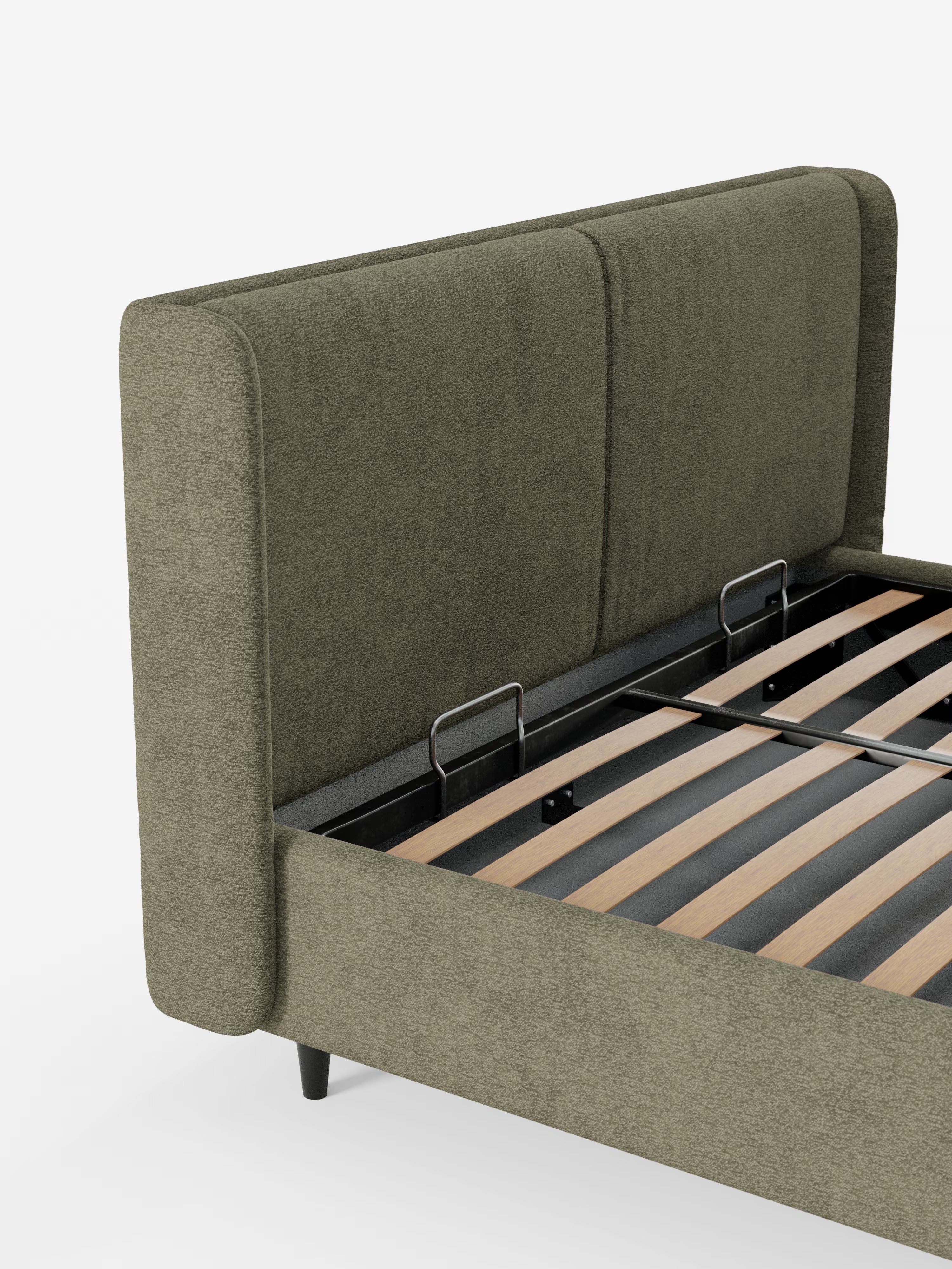 Ecco una versione riscritta della tua frase utilizzando i dati del prodotto forniti: Primo piano del letto di design VALKIRIA di Letti.store, una struttura imbottita color verde oliva (letto imbottito) caratterizzata da un'alta testiera avvolgente con due morbidi cuscini e cuciture verticali che ne sottolineano il design contemporaneo. Il letto è sostenuto da gambe affusolate nere e include doghe in legno per il sostegno del materasso, oltre a un pratico vano contenitore. Rivestito in tessuto certificato